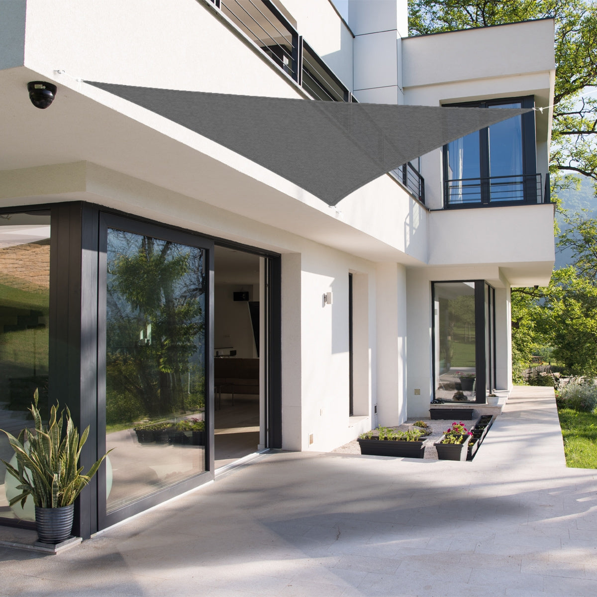 A triangular sunshade in gray, attached to a modern building.