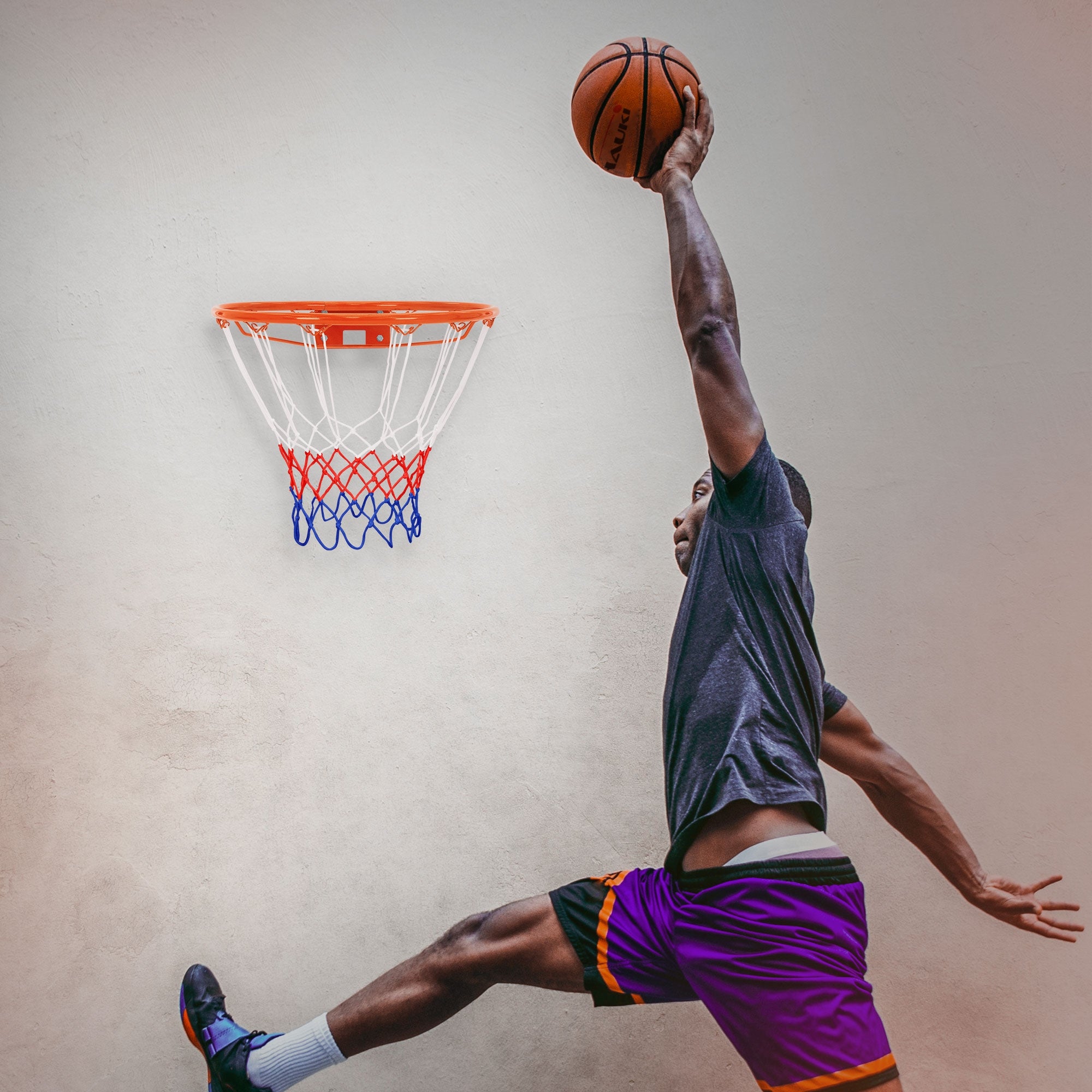 Un giocatore di basket salta e lancia la palla nel canestro su una parete.