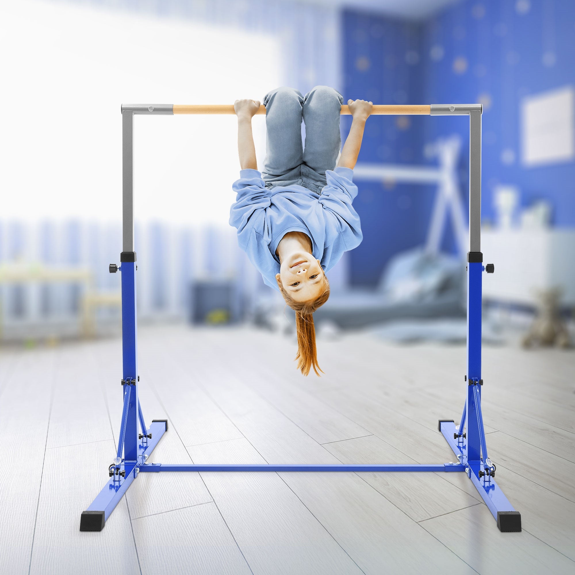 Enfant suspendu à l'envers sur un appareil de gymnastique bleu dans une pièce lumineuse.