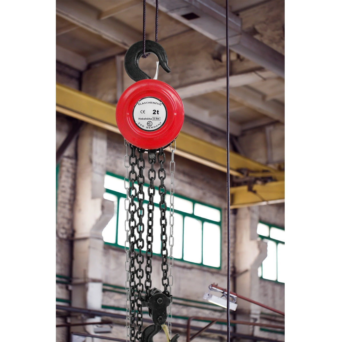 Rode takel met ketting, hangt in een industriële omgeving.