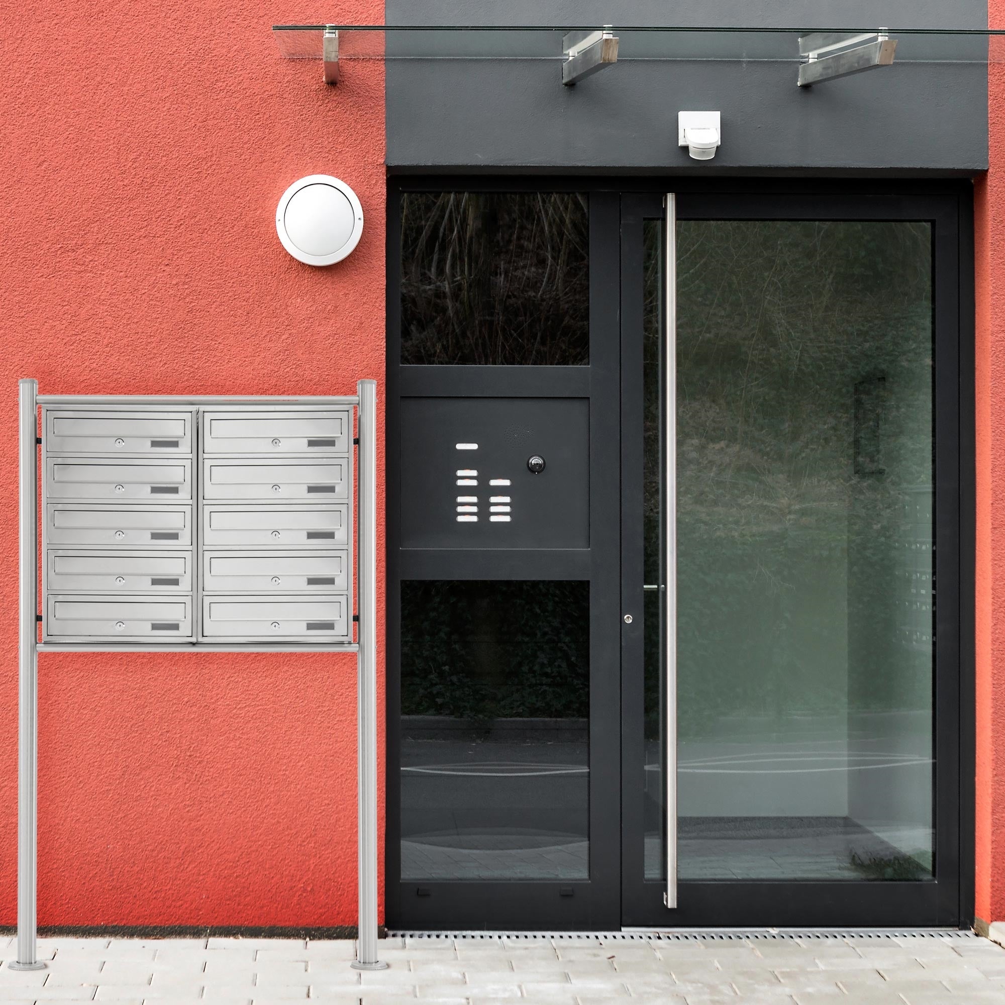 Entrance door with glass and a silver mailbox next to it.