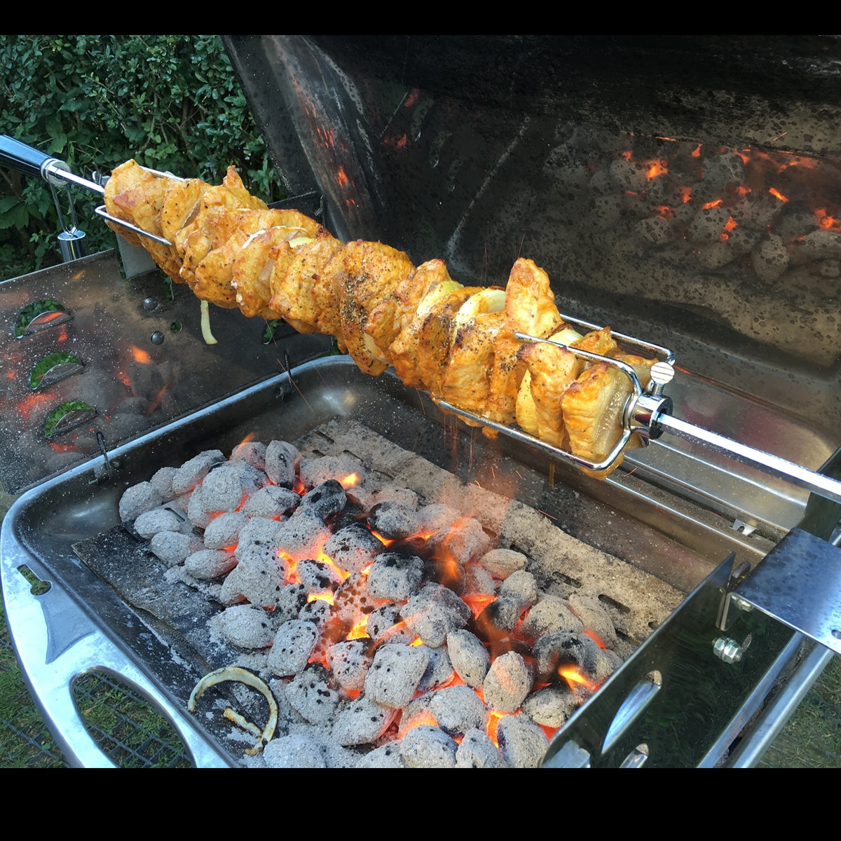 Rożen z marynowanym kurczakiem na grillu nad żarzącymi się węglami.