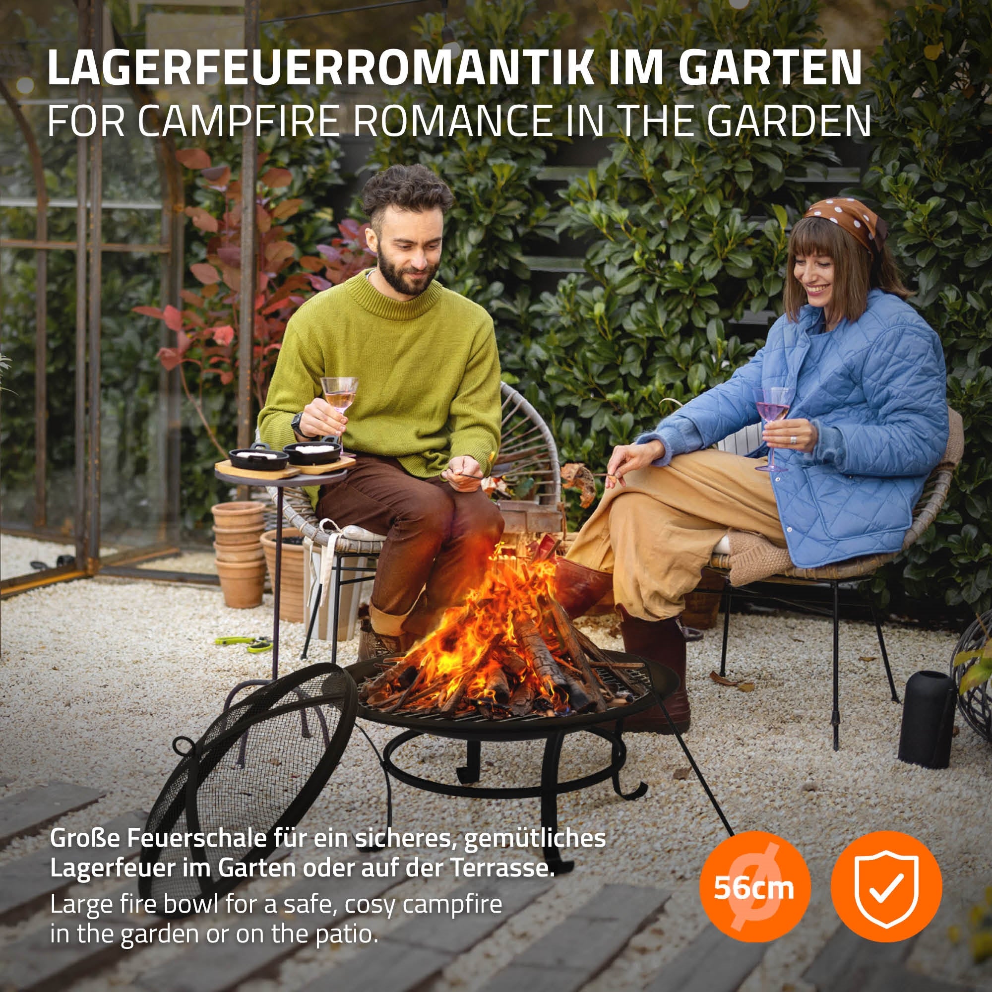 Een paar zit bij het kampvuur in de tuin, omringd door stoelen.