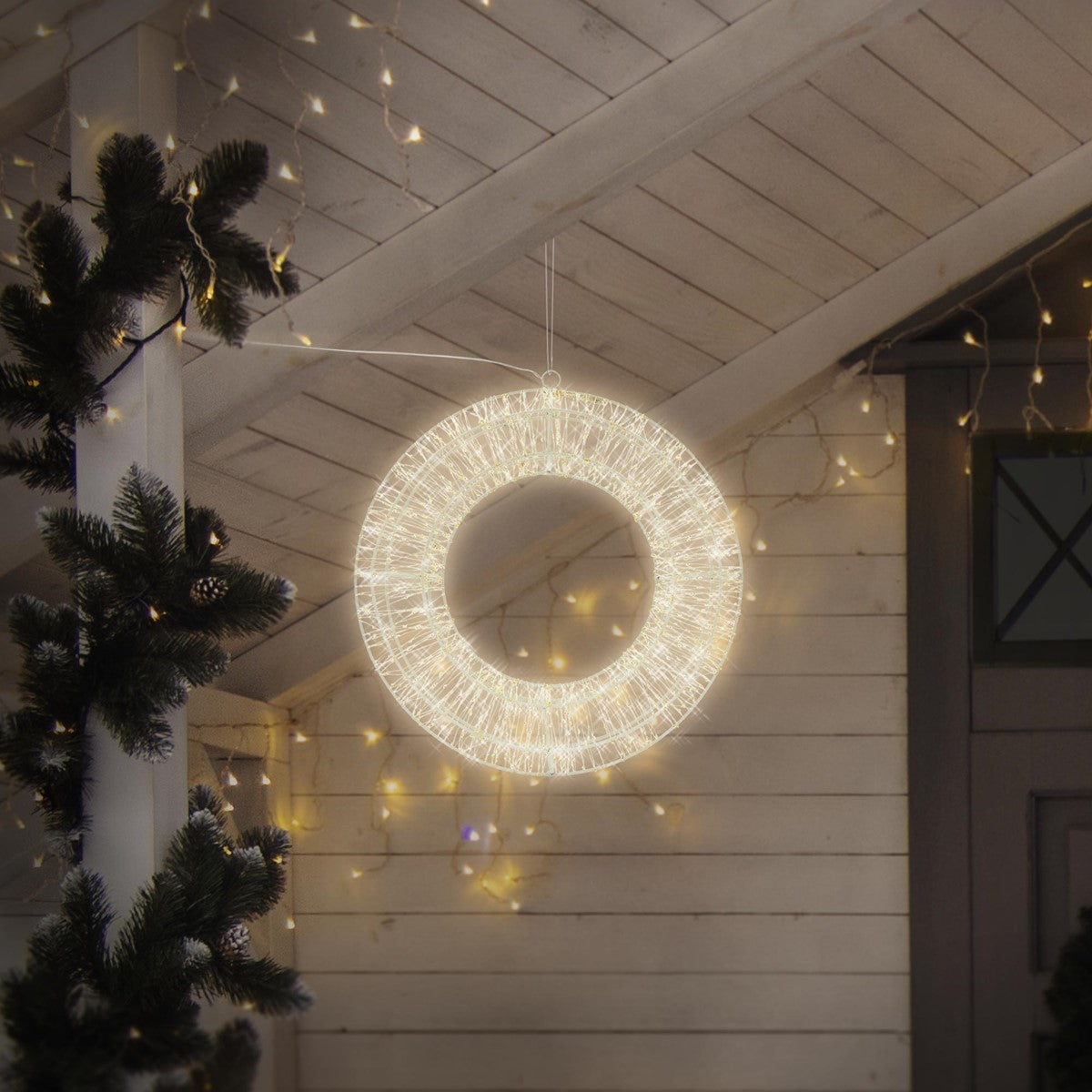 Corona luminosa rotonda appesa in una stanza con decorazioni natalizie.