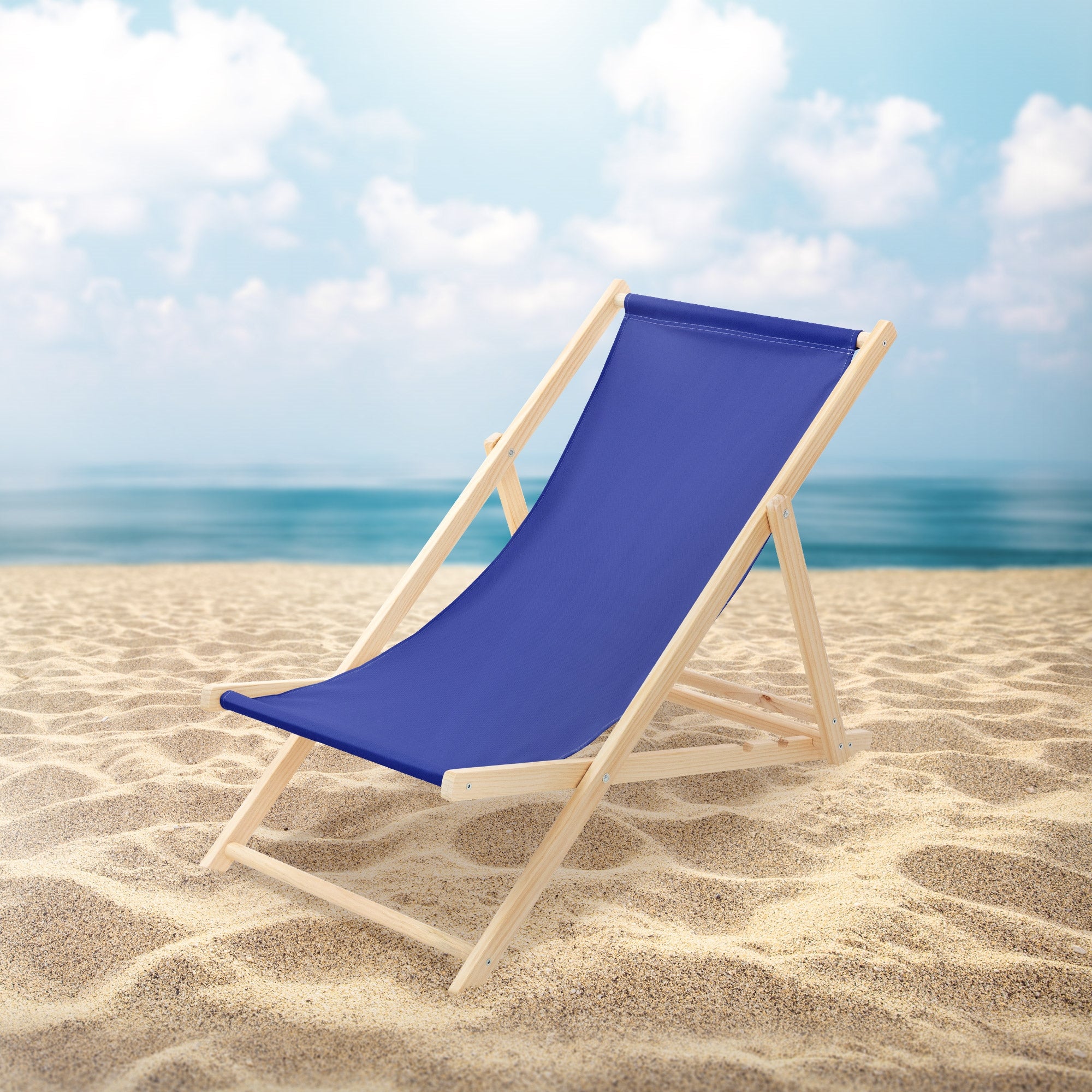 Blue deck chair on the beach with sea and clouds in the background.