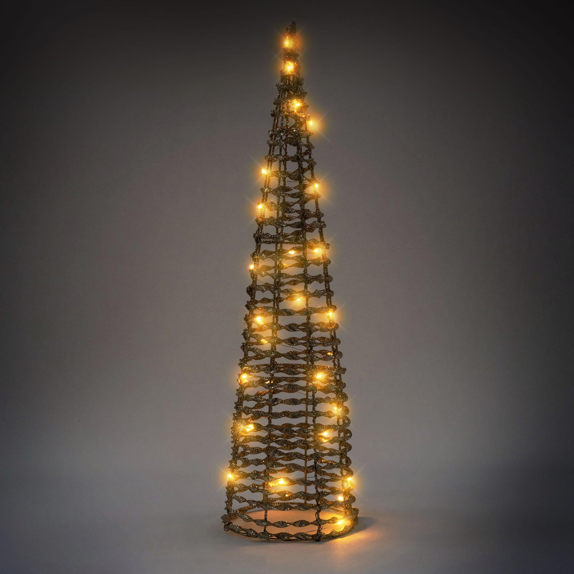 Un sapin de Noël décoratif en fil avec des lumières, devant un fond sombre.