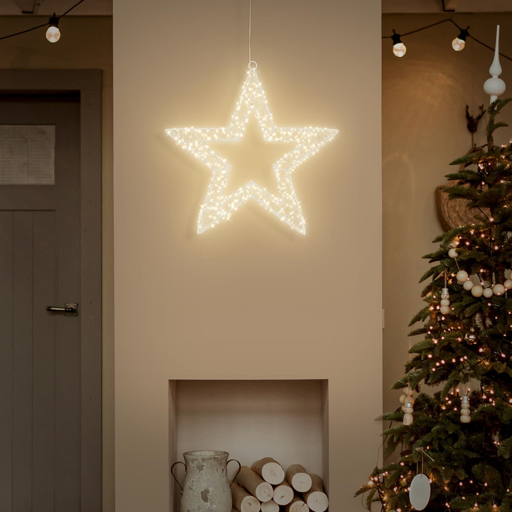 Étoile lumineuse blanche suspendue à un mur au-dessus d'un sapin de Noël.
