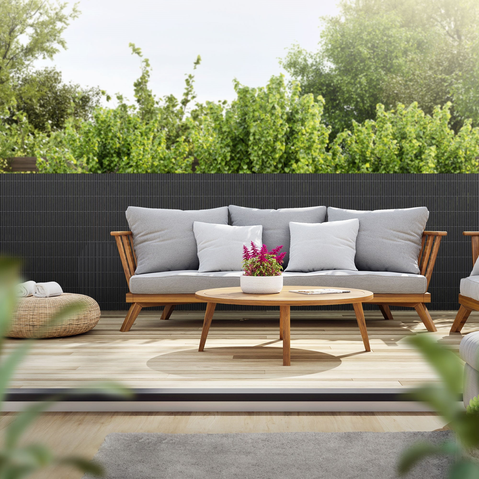 Hyggelig terrasse med sofa, bord og planter i baggrunden.