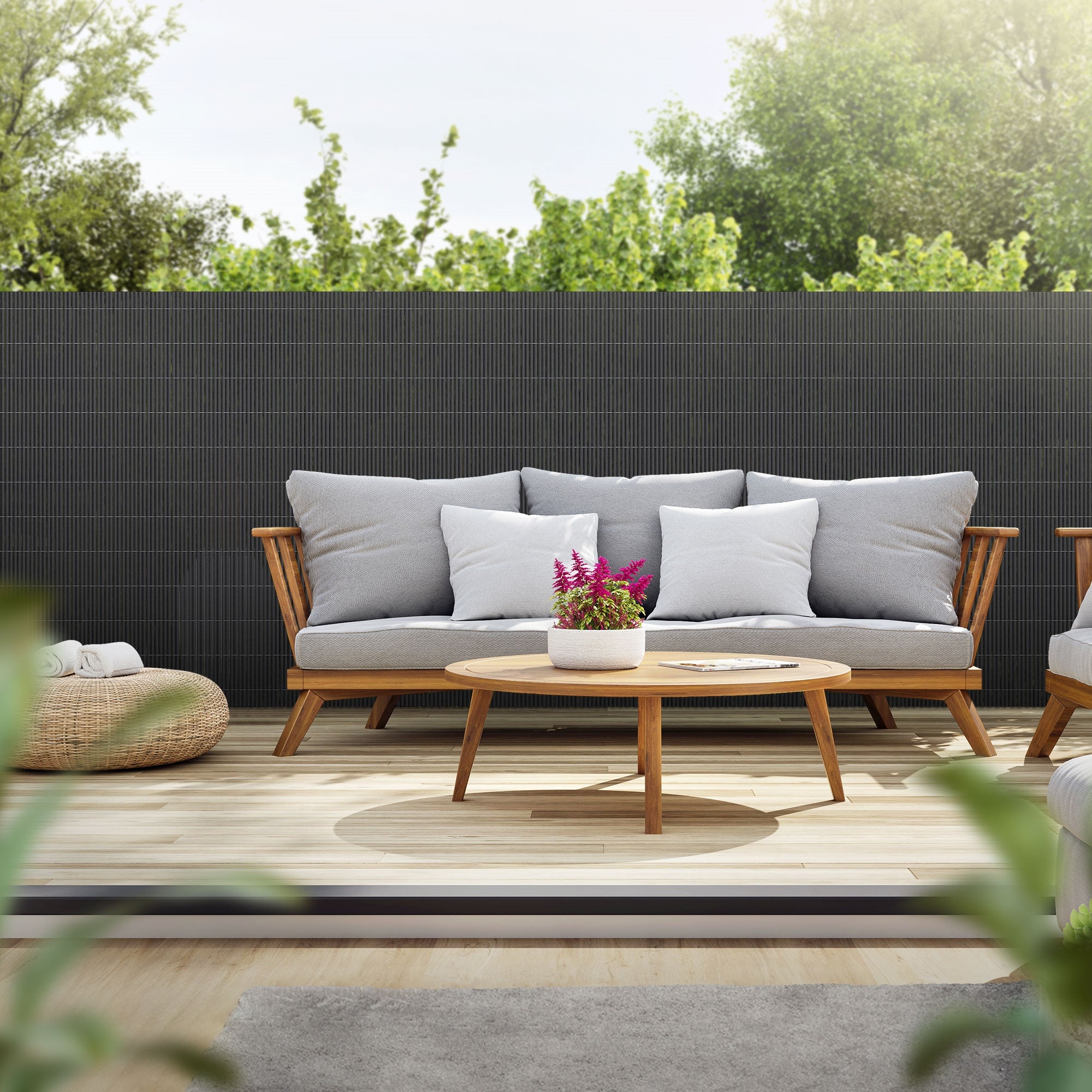 Skærm i antracit, sofa, bord og planter udendørs.
