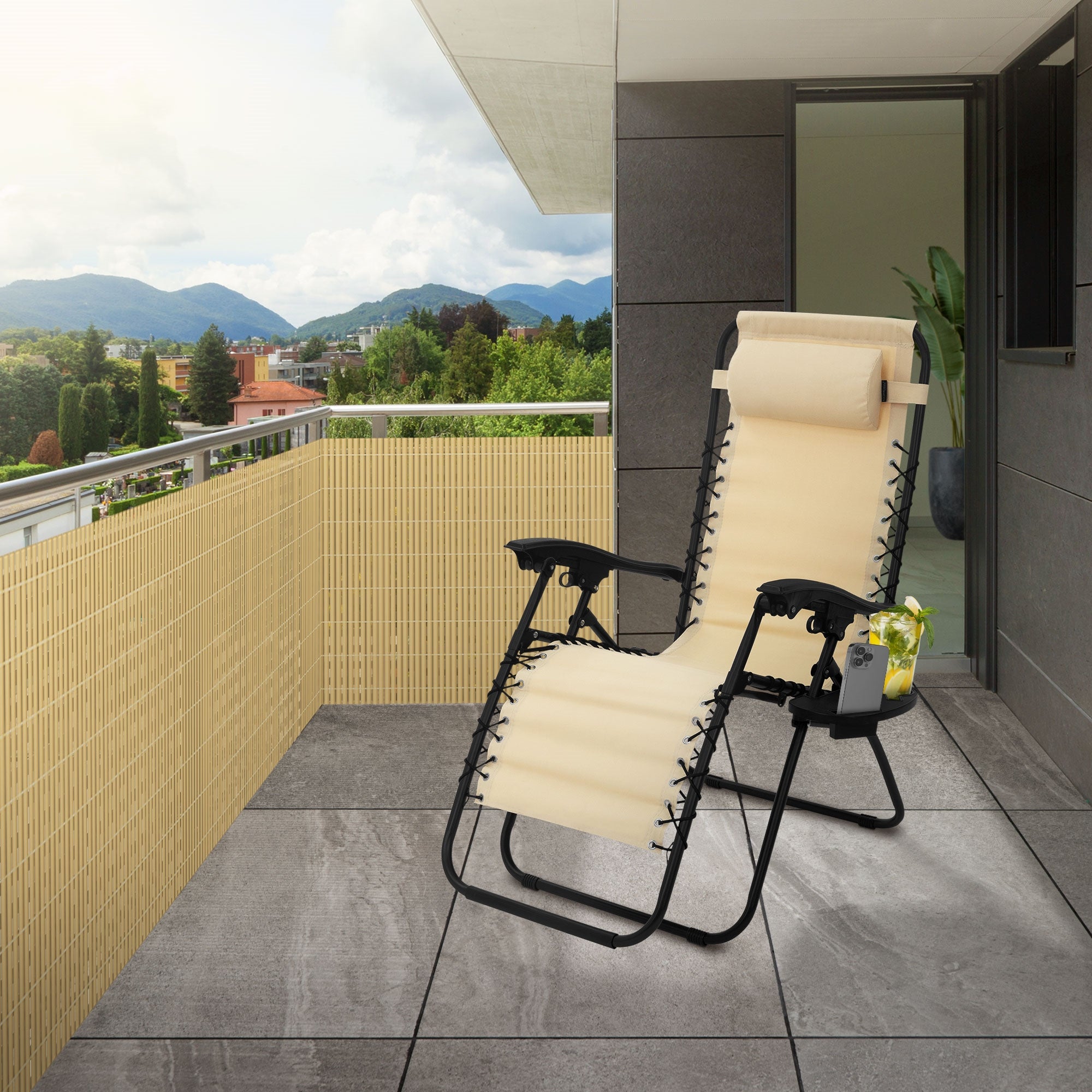 Ein Balkon mit einem Liegestuhl und einer Bambusmatte als Sichtschutz.