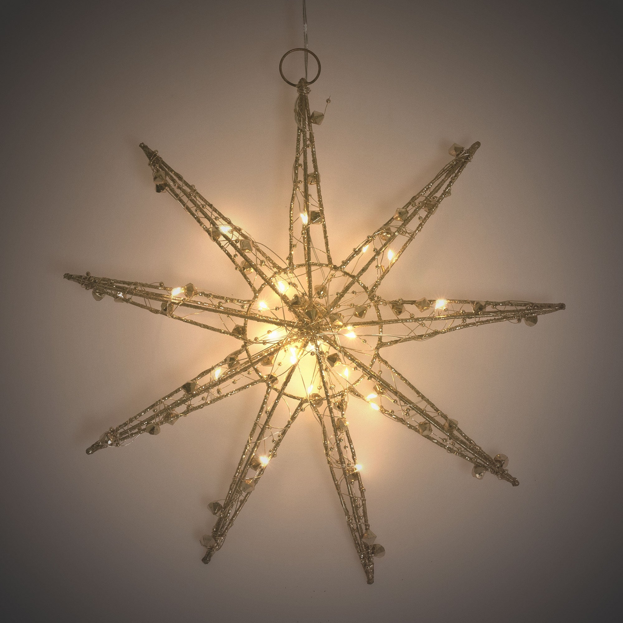 Een grote, verlichte kerstster hangt aan een muur.