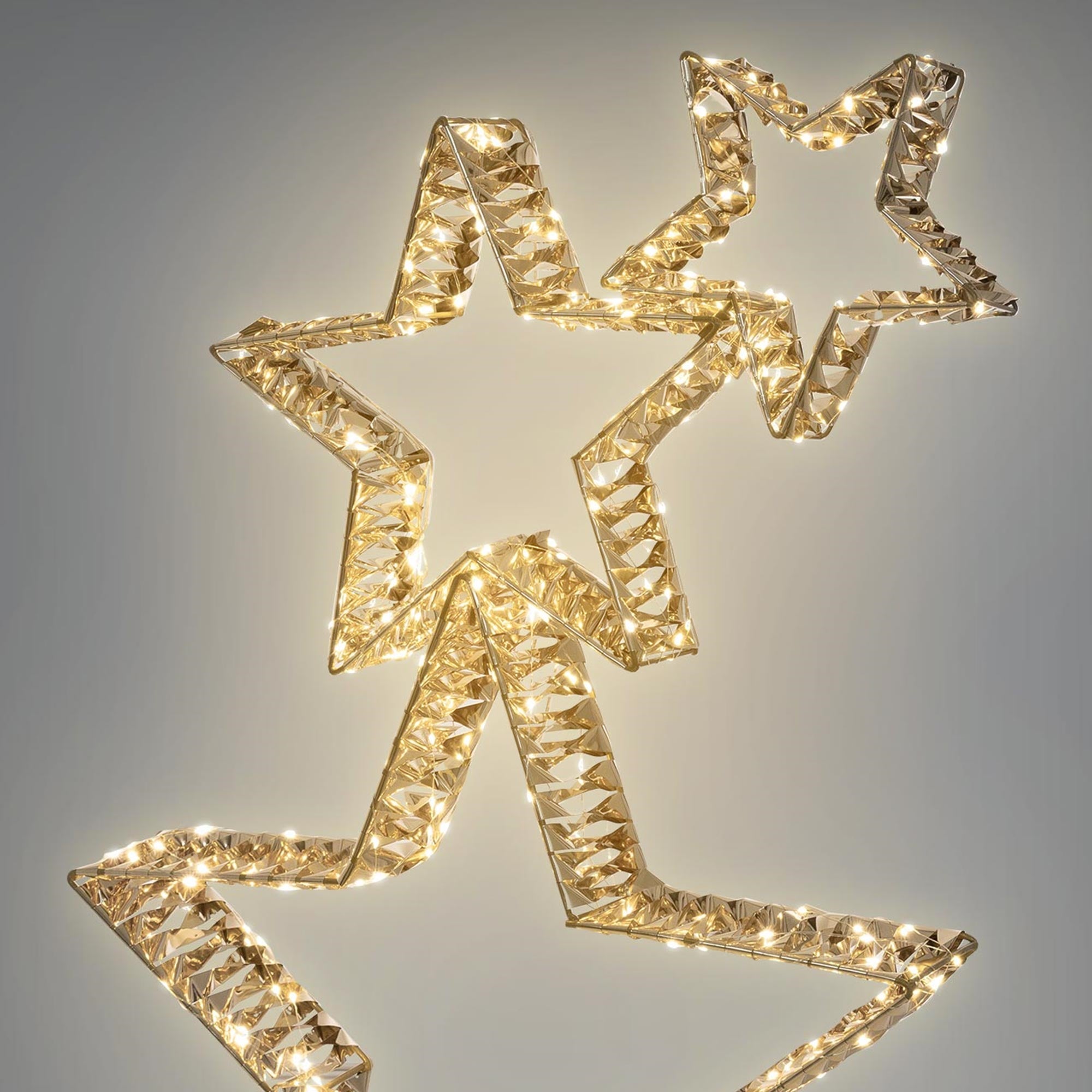 Goldene Sterne mit Lichtern, auf grauem Hintergrund.