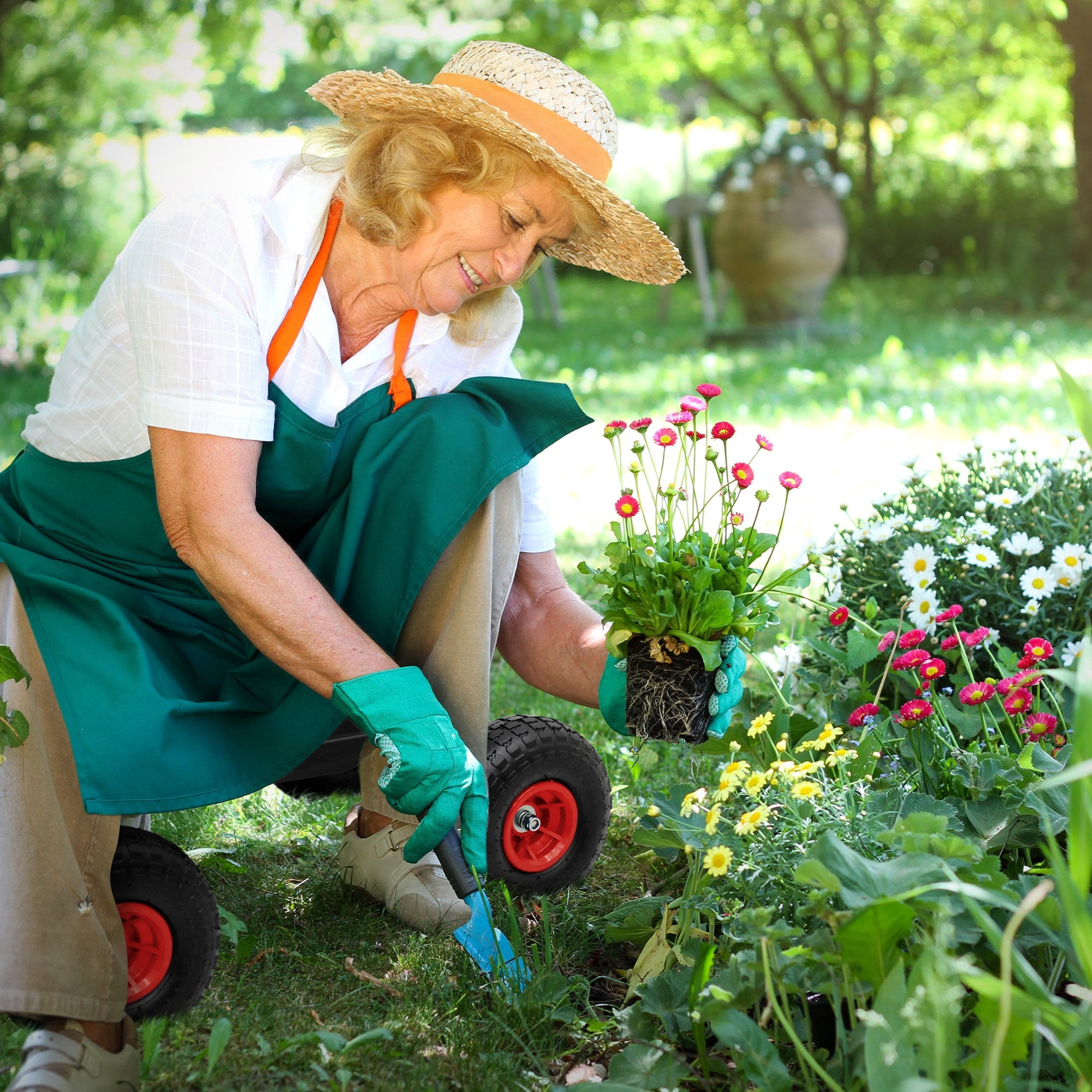 Oudere vrouw plant bloemen in de tuin, draagt een hoed en handschoenen.