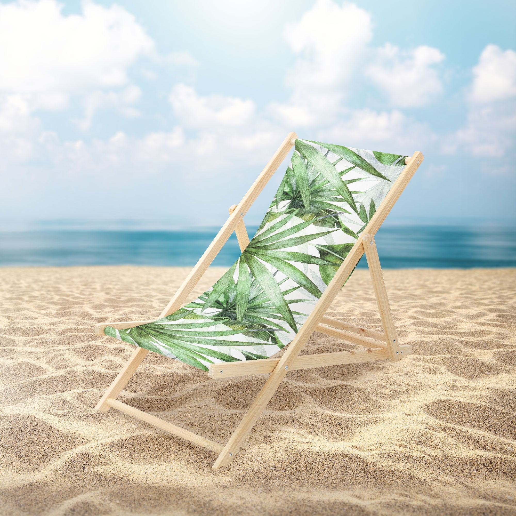 Fekvőszék a strandon pálma mintával és háttérben a tengerrel.