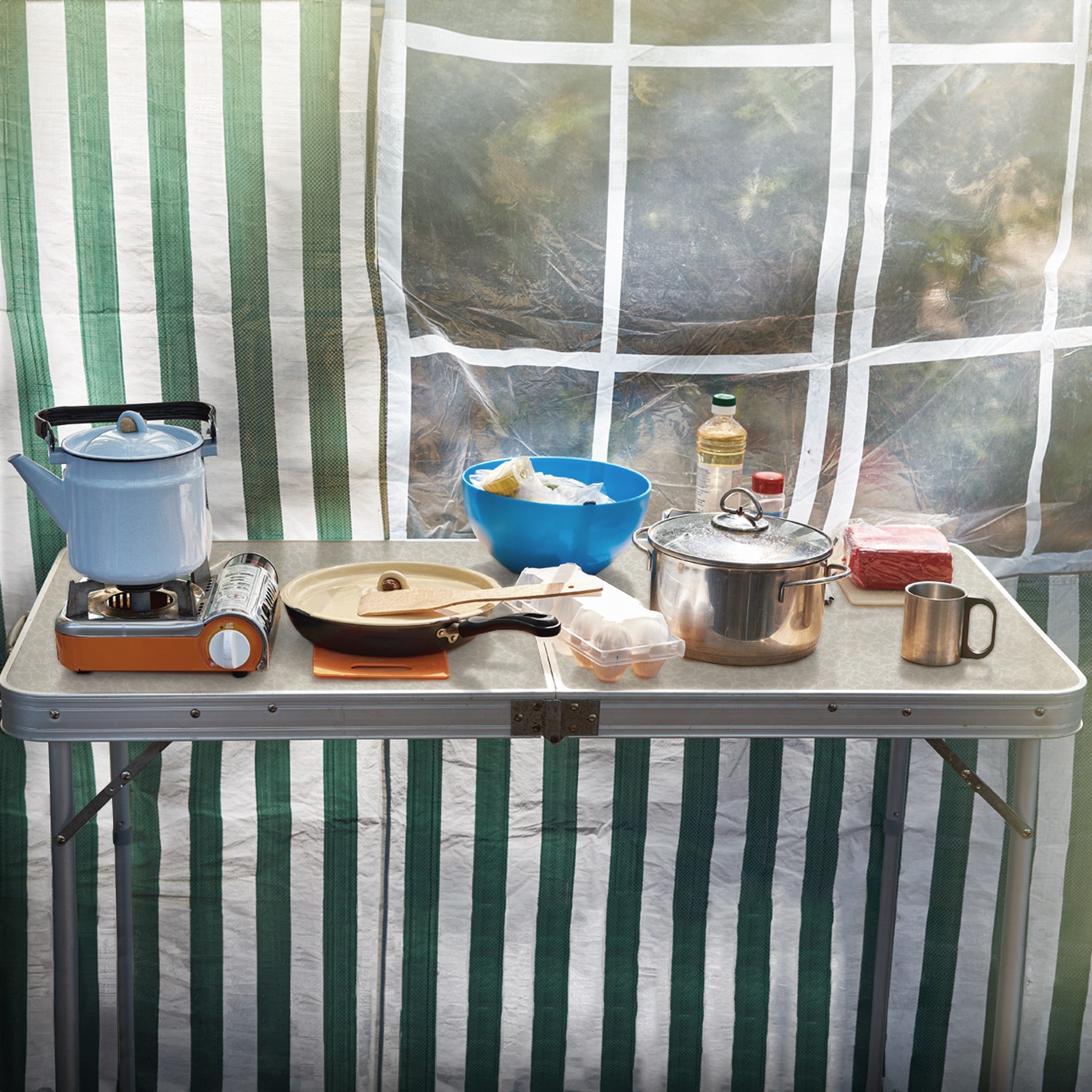 Réchaud de camping, casseroles et aliments sur une table dans la tente.