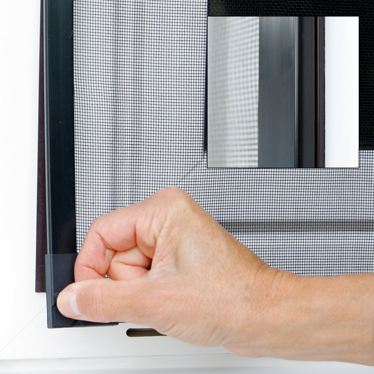 Hand installing an insect protection screen at a window.