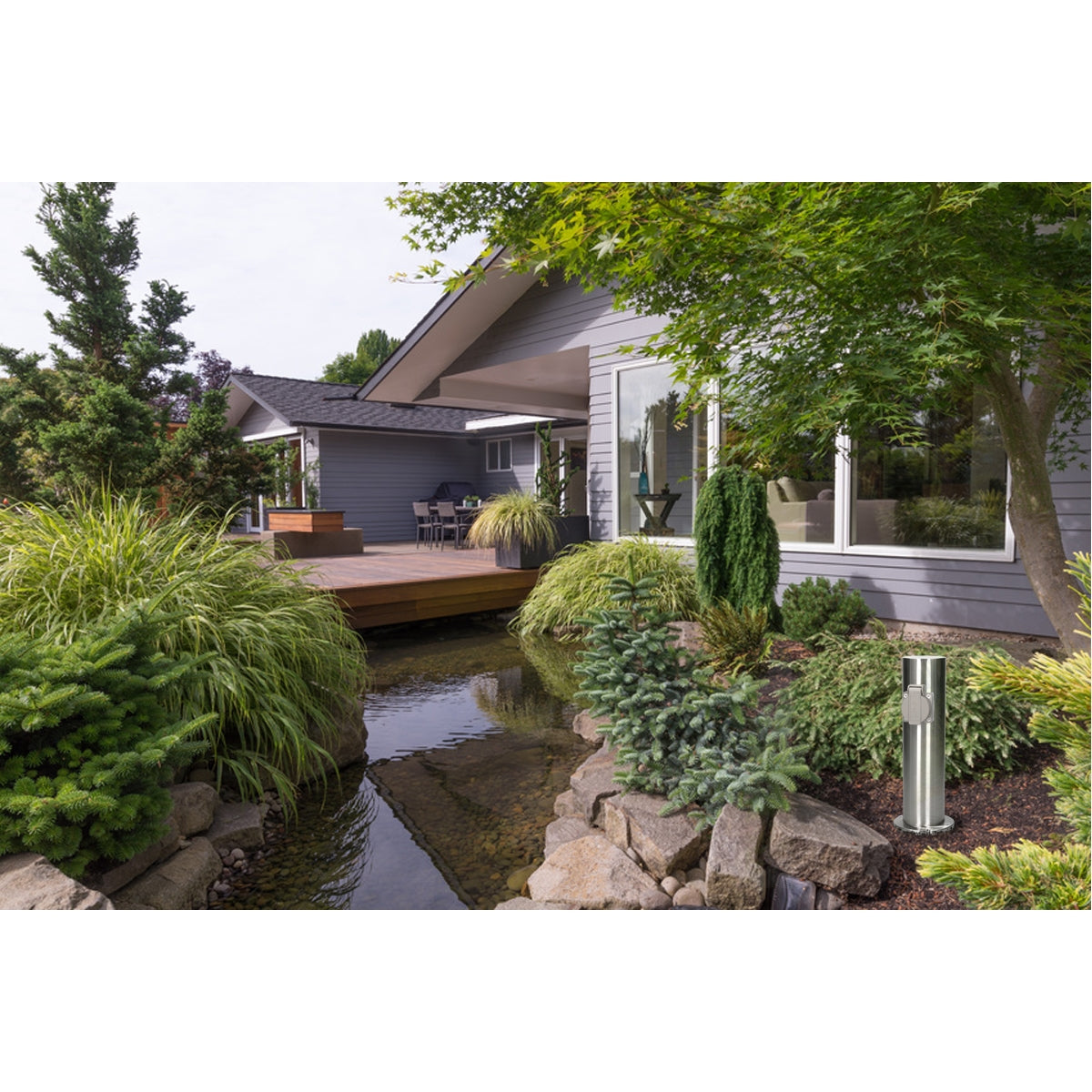 Gartenansicht mit einem kleinen Teich, Pflanzen und einem modernen Haus im Hintergrund.