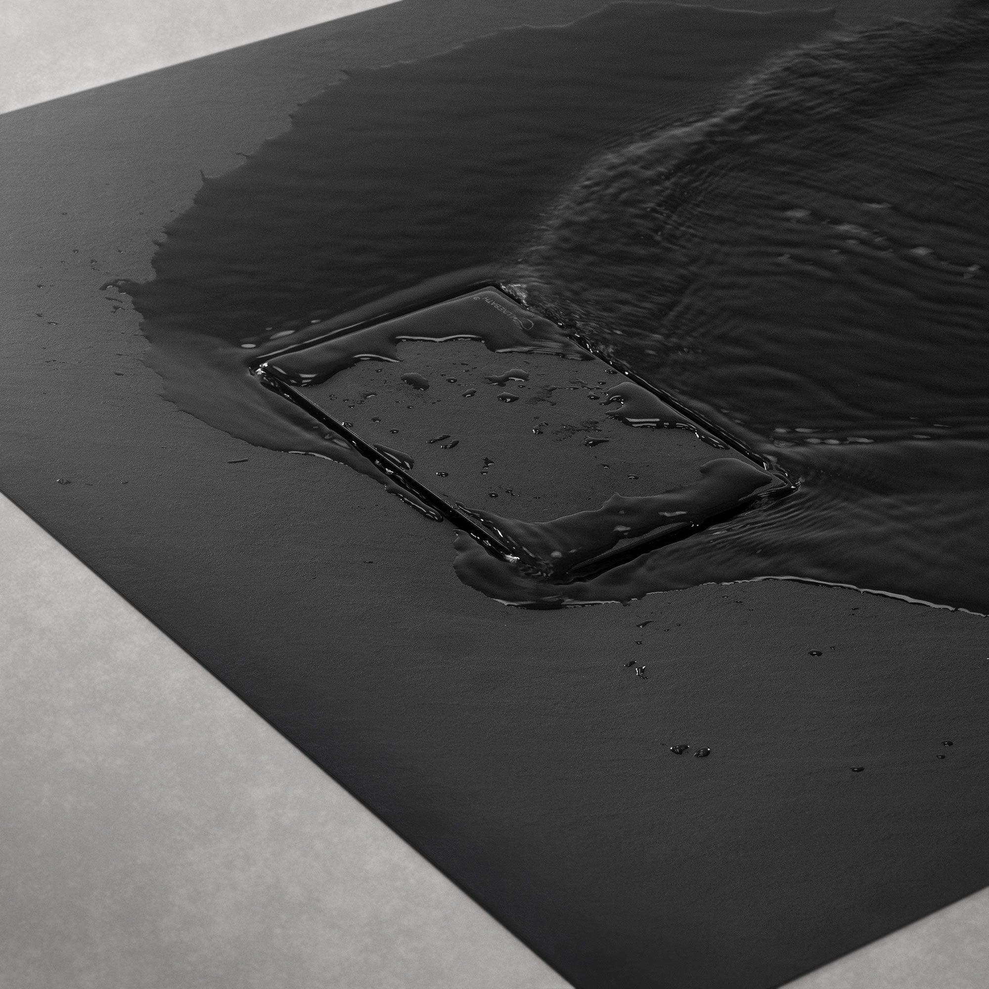 Schwarze Fläche mit Wasser, das auf eine rechteckige Ablaufrinne fließt.