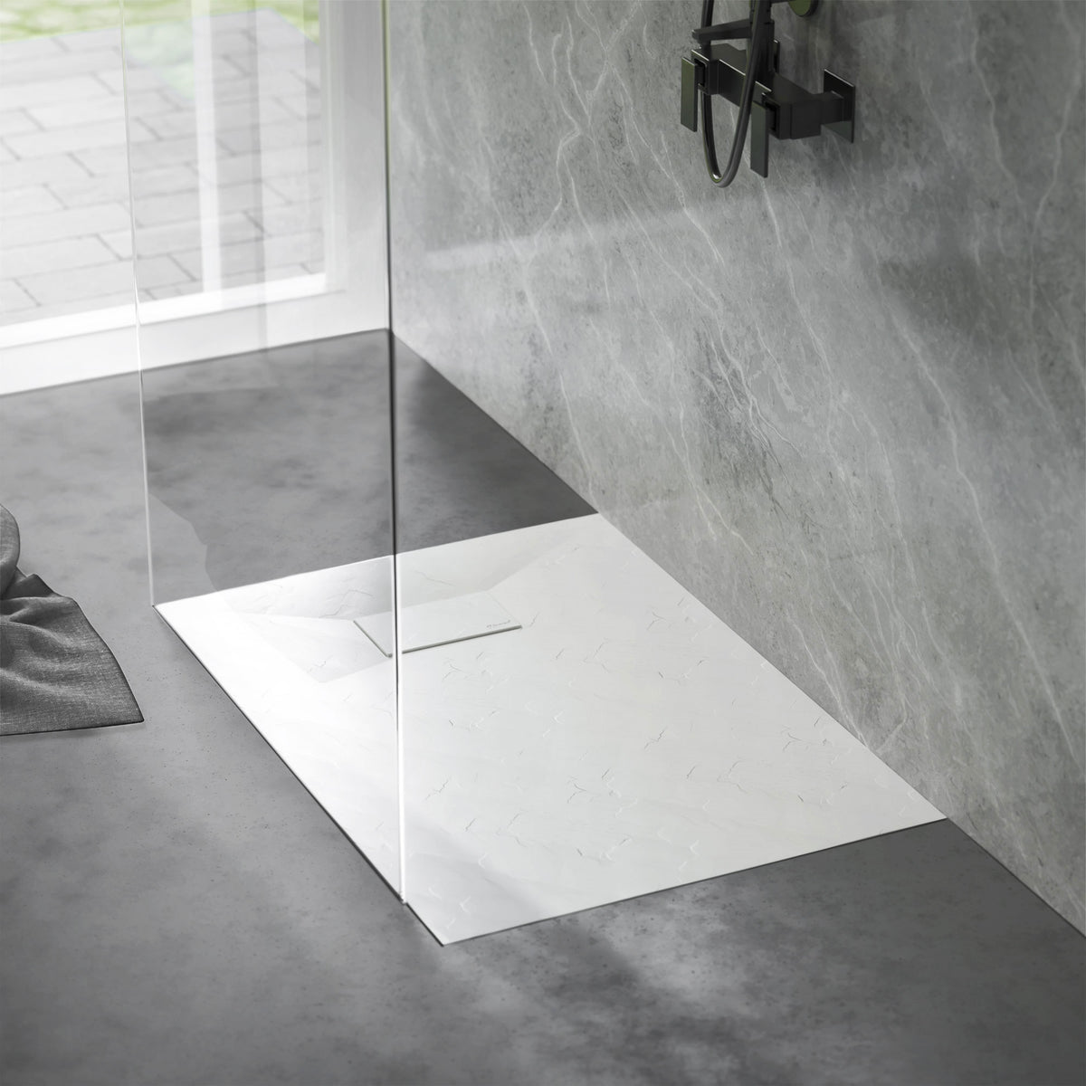Espace de douche avec une surface de douche antidérapante et un mur en verre.