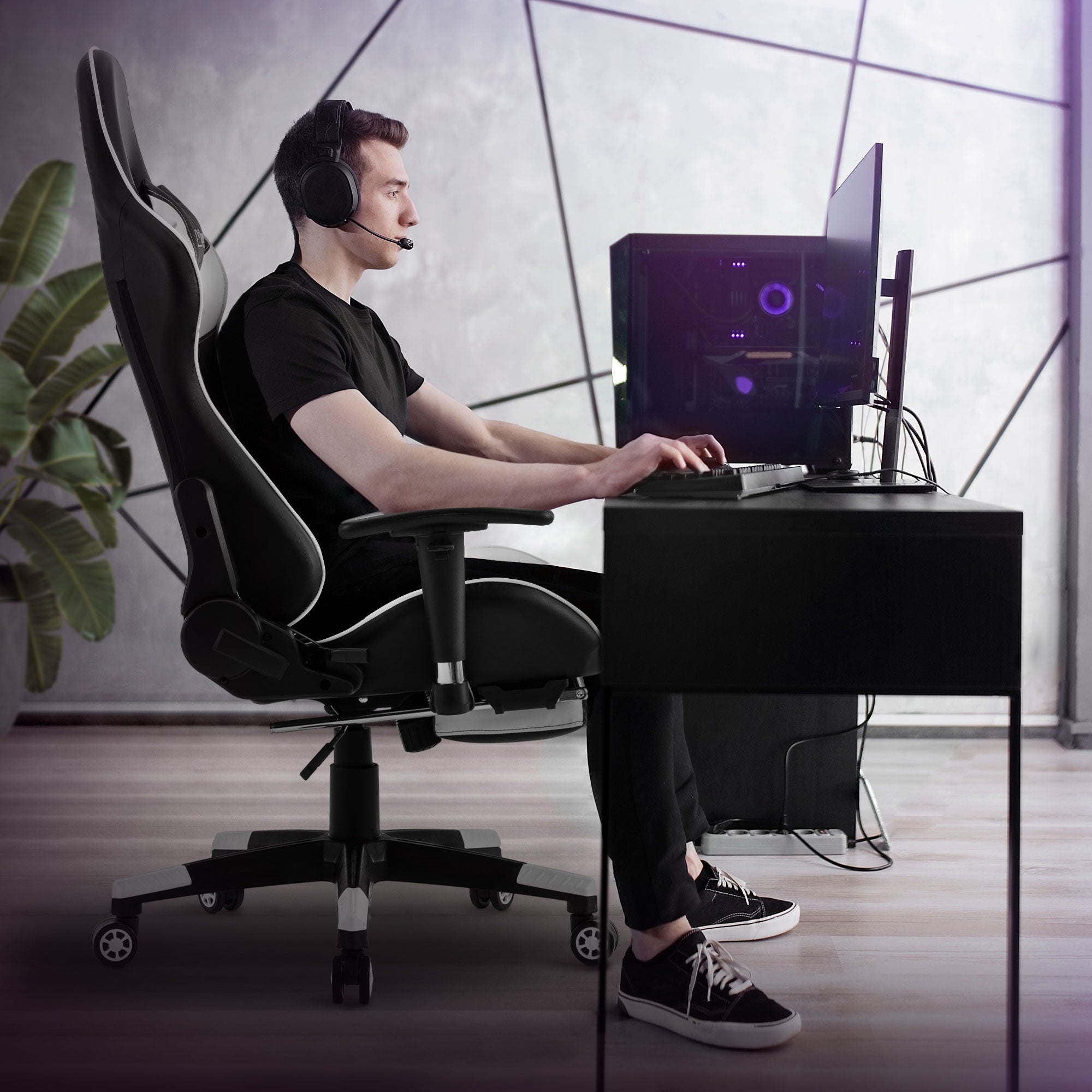 Mann sitzt an einem Schreibtisch in einem Gaming-Stuhl und trägt ein Headset.
