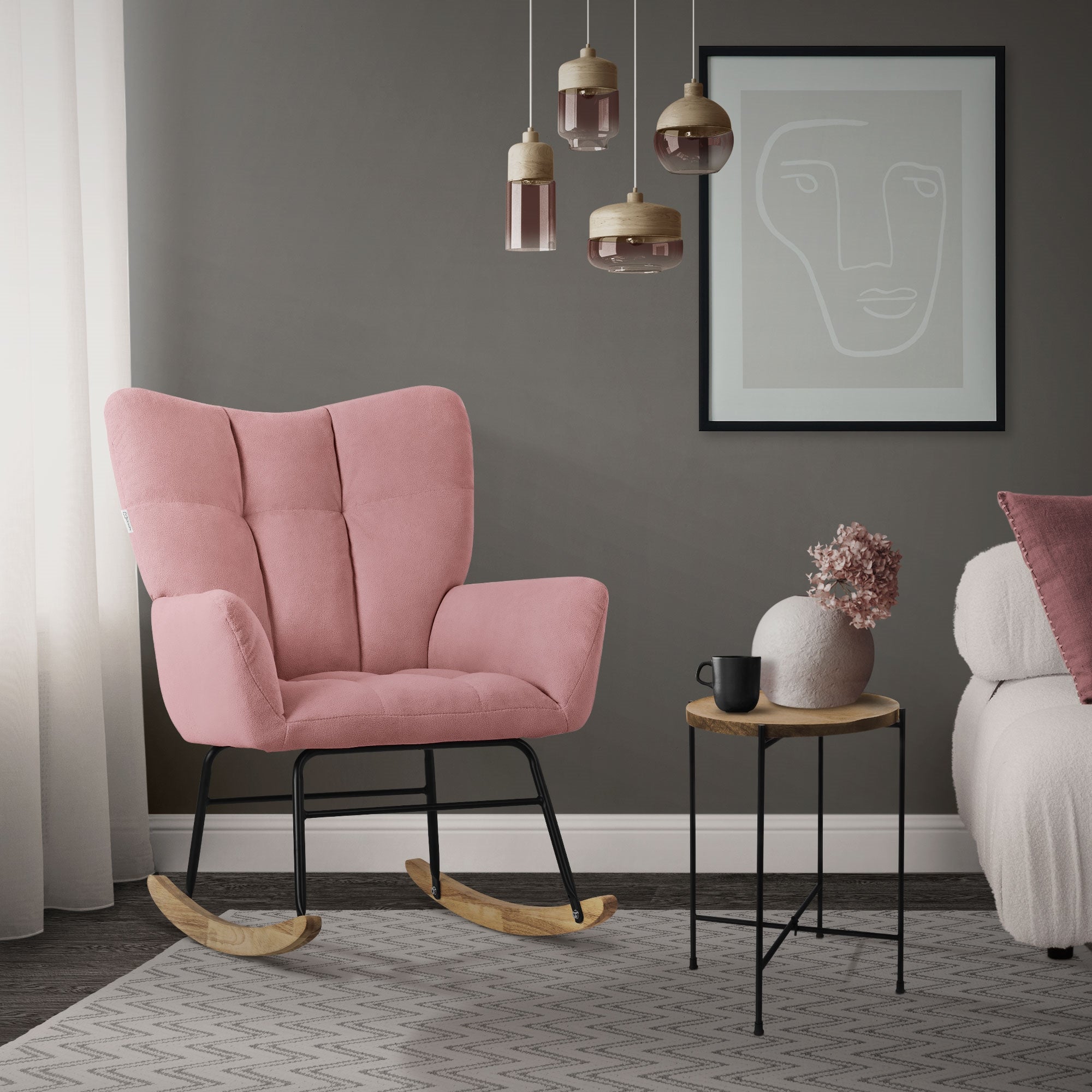 A pink rocking chair stands in a room with gray walls and a plant on the table.