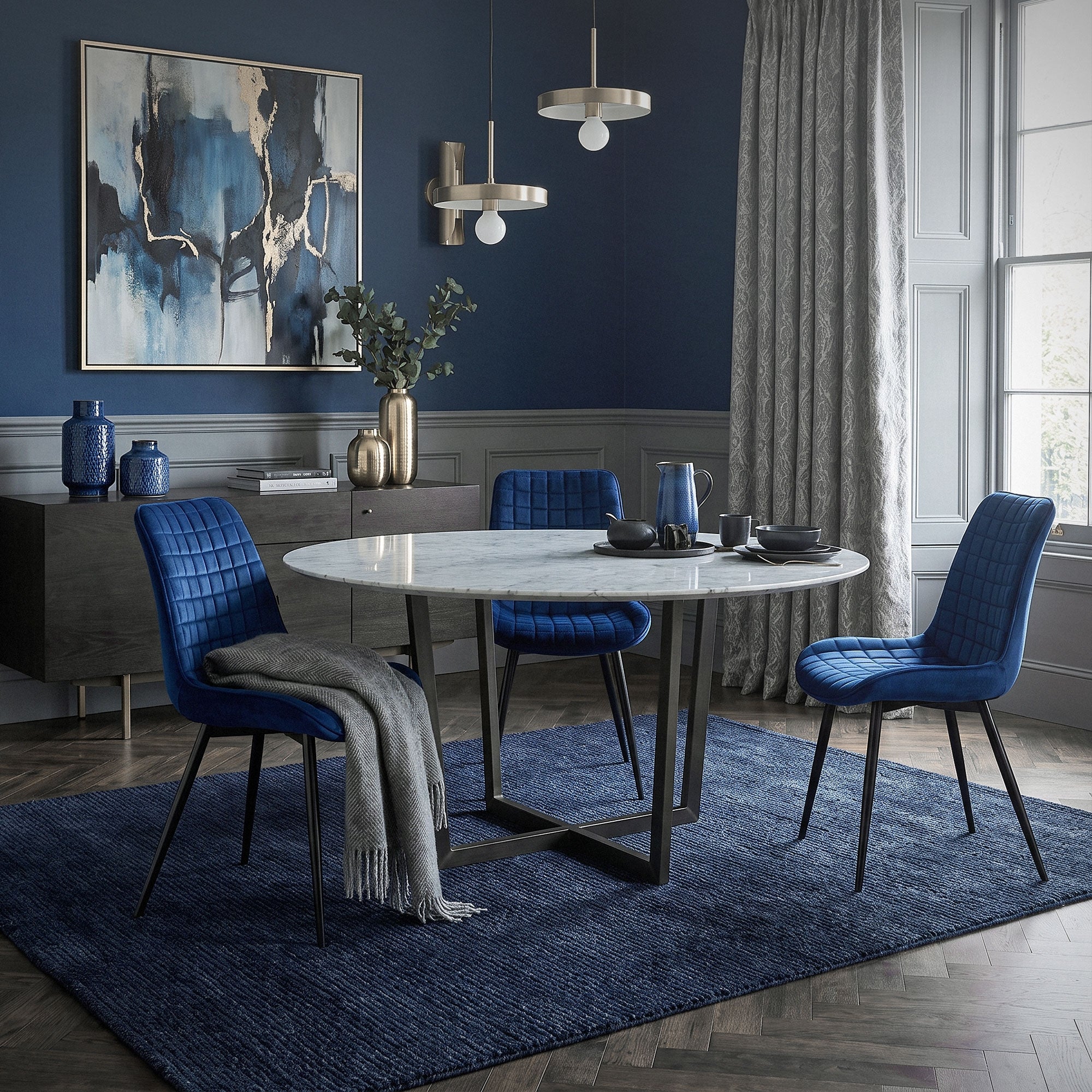 Table ronde avec des chaises bleues dans une pièce élégante avec une œuvre d'art au mur.