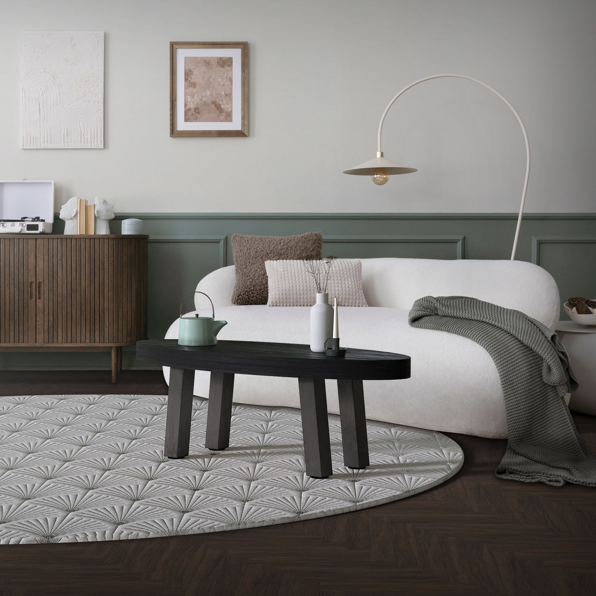 Wohnzimmer mit Sofa, Tisch und Dekoration auf einem runden Teppich.