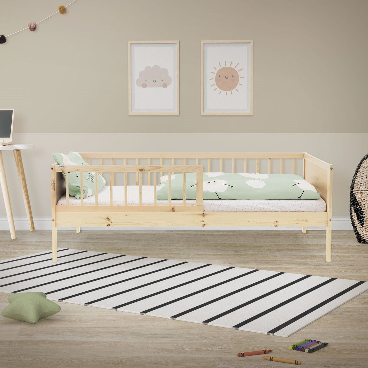 Een licht houten kinderbed met groene beddengoed in een kamer.