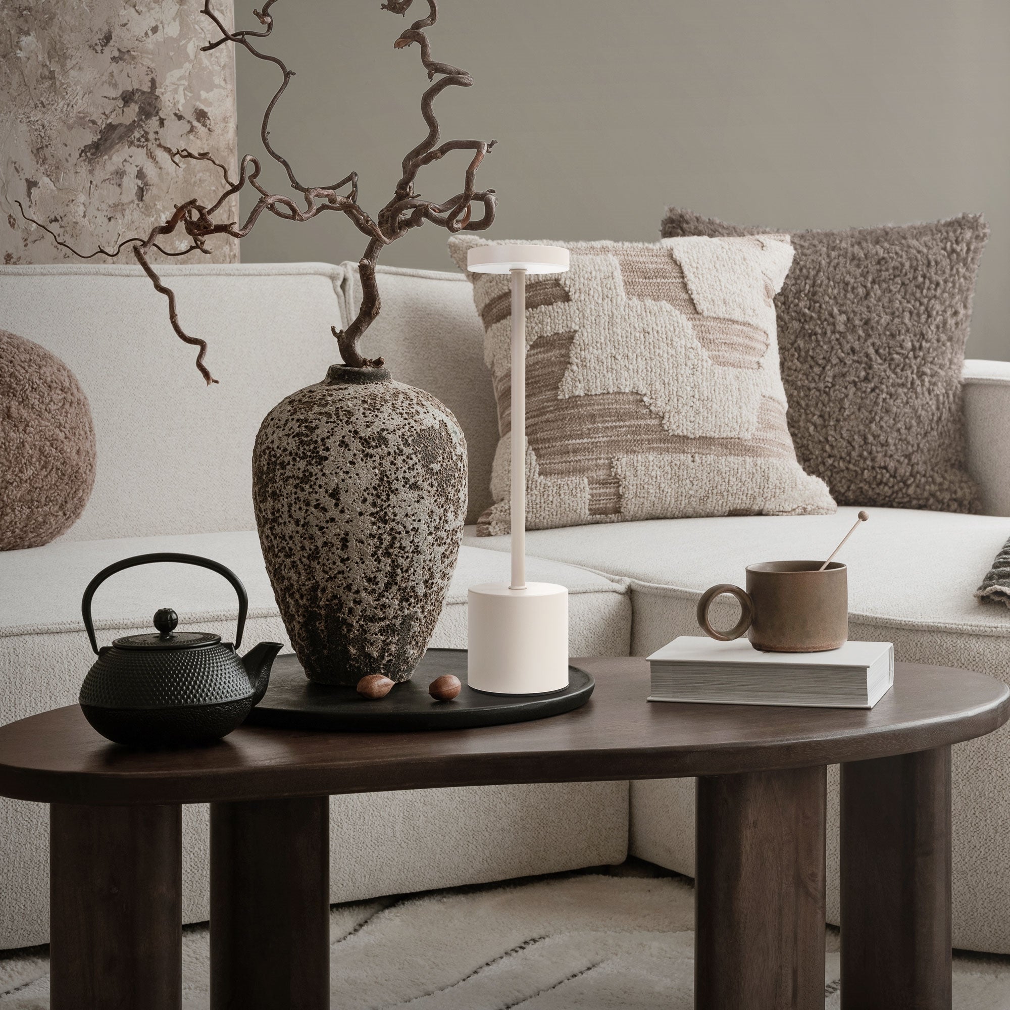 Wohnzimmer mit Stehlampe, Vase, Teekanne und Tasse auf einem Tisch.
