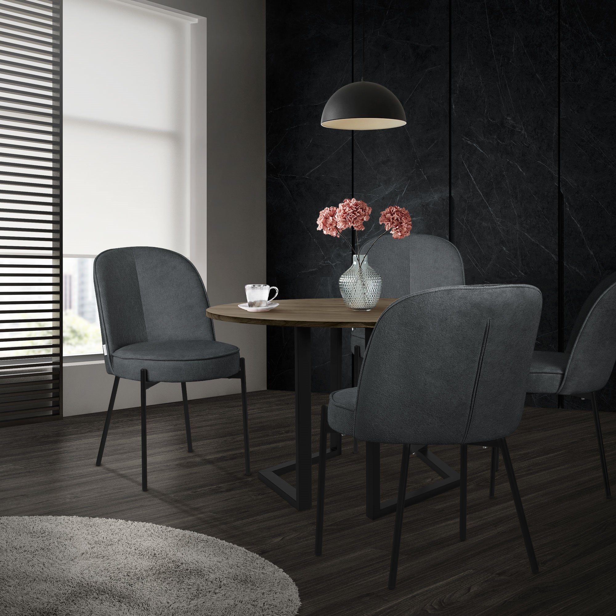 Un tavolo rotondo con quattro sedie grigie e un vaso con fiori.