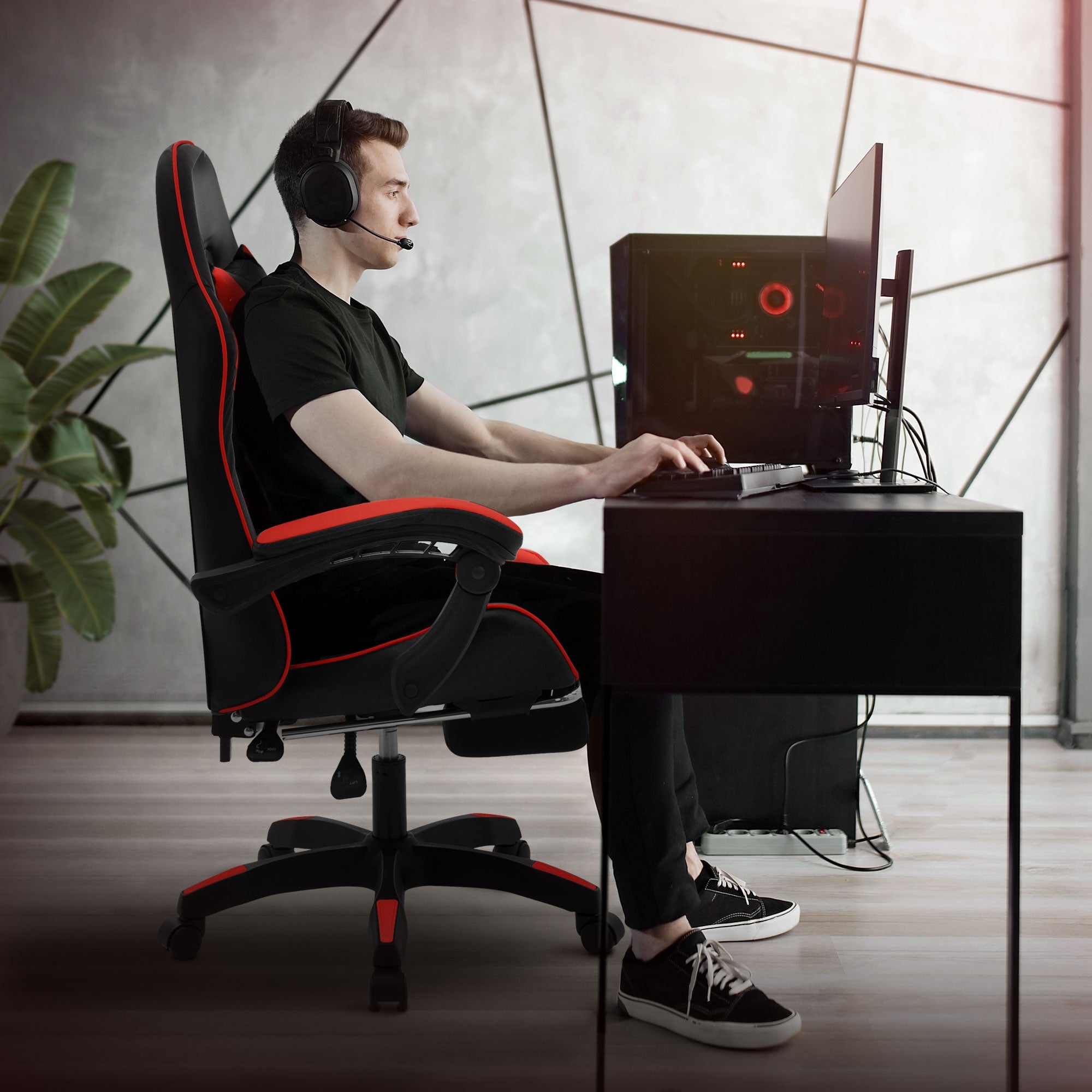 Junger Mann sitzt in einem Gaming-Stuhl und spielt am Computer.