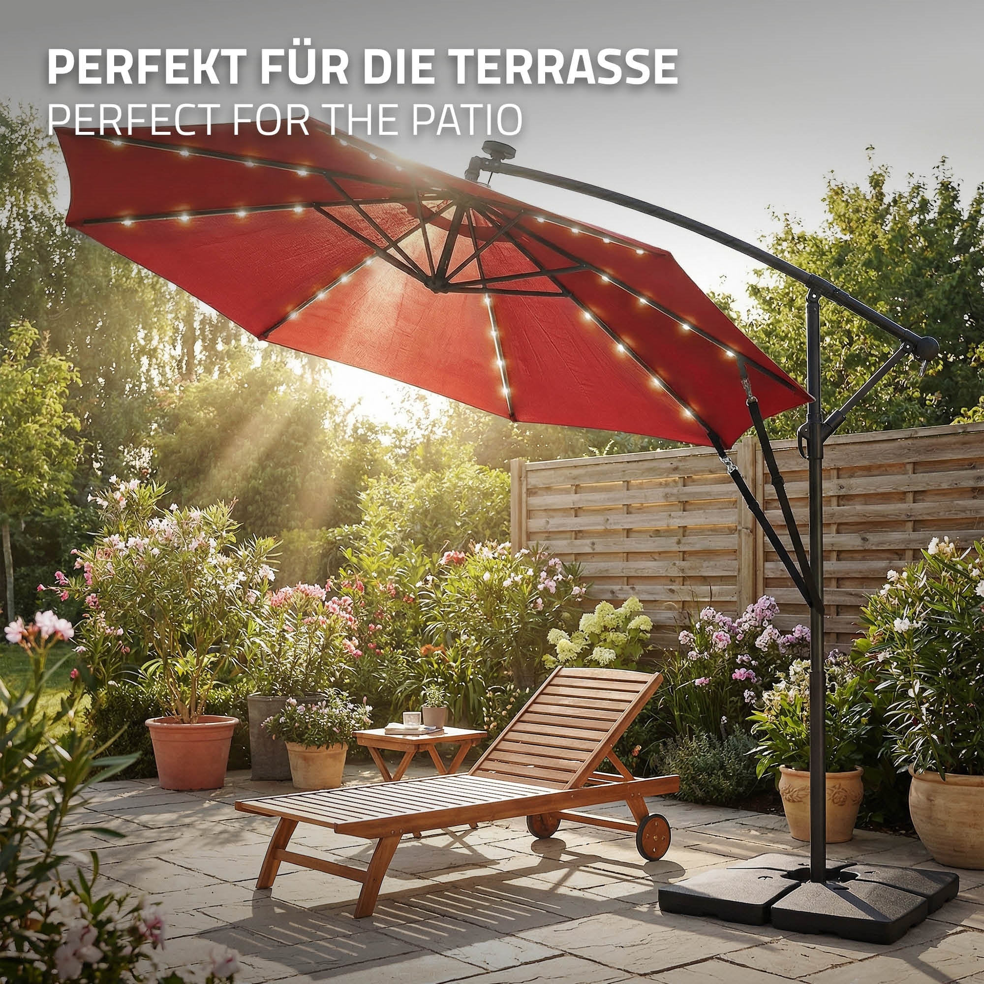 Rode parasol met lichtsnoer, naast een ligstoel op een terras.