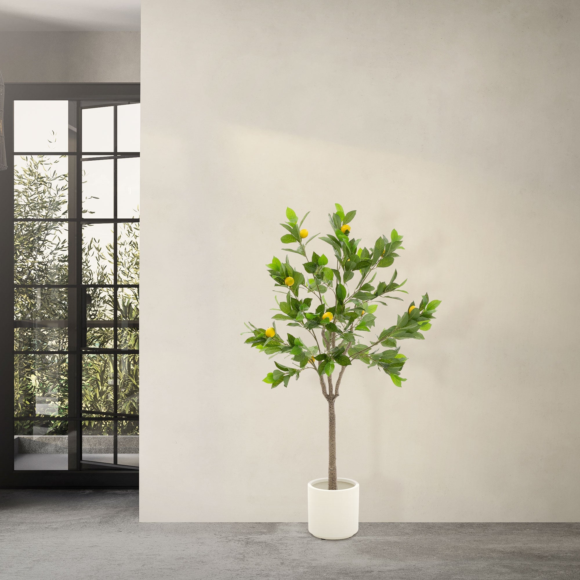 Un albero artificiale con foglie verdi e frutti gialli in un vaso bianco.