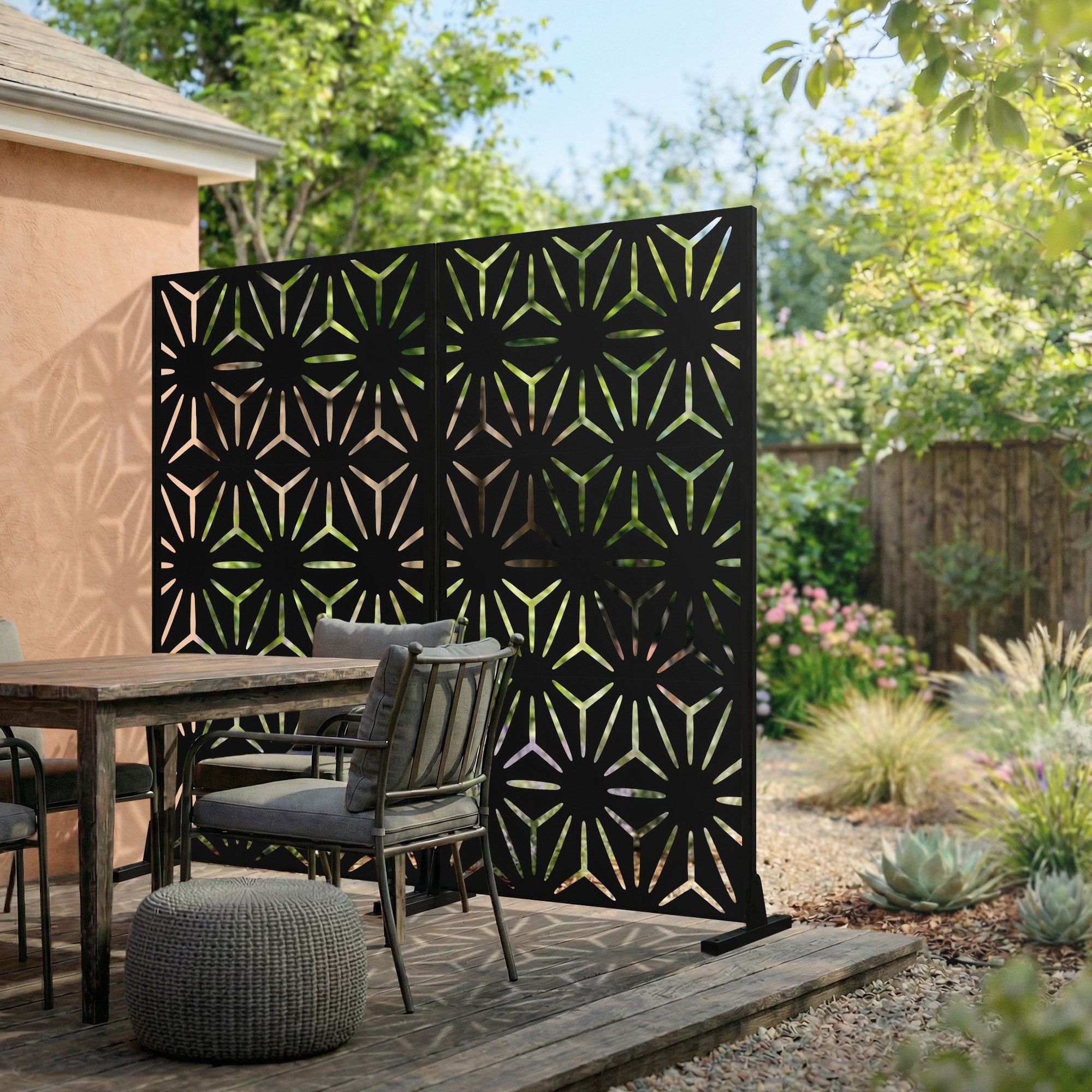 Ein Garten mit einem Sichtschutz aus drei Panels, umgeben von Pflanzen und einem Tisch.