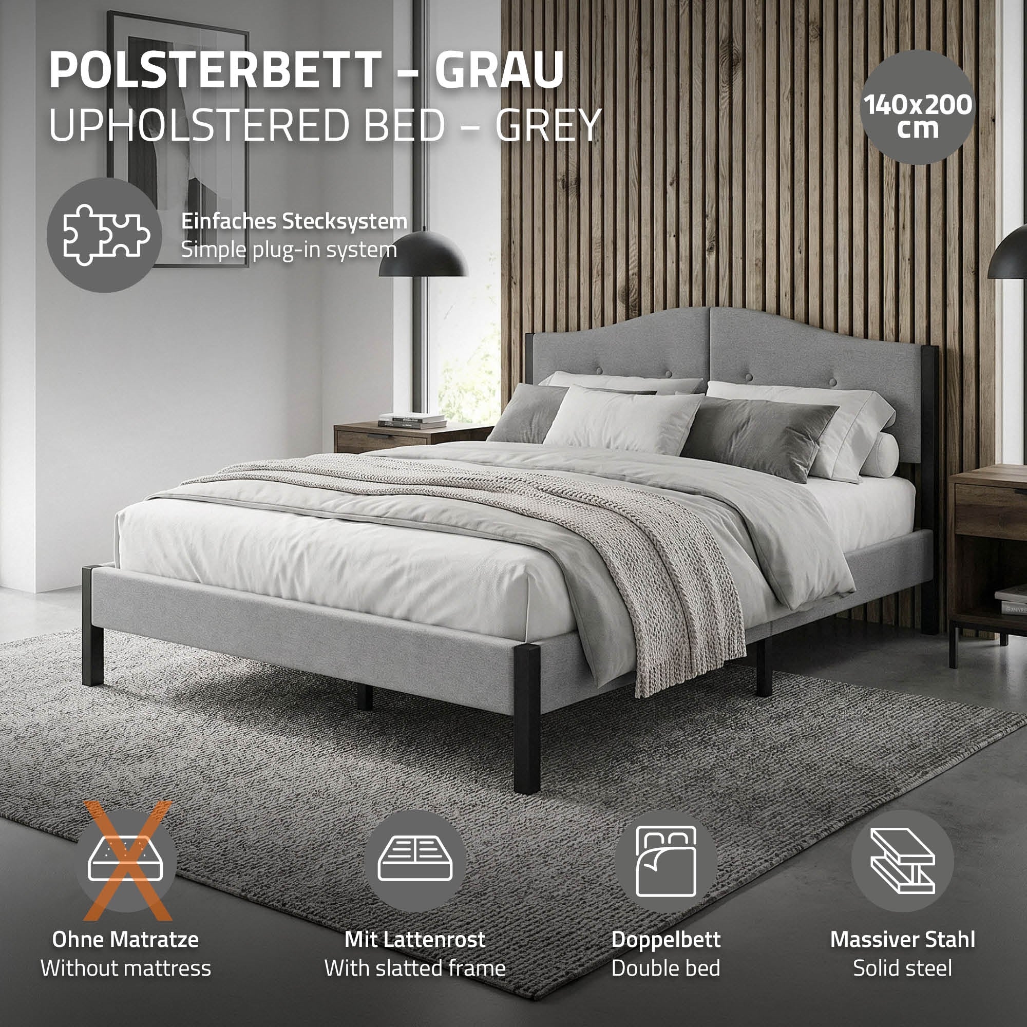 Een grijs gestoffeerd bed met een deken en kussens op een tapijt.