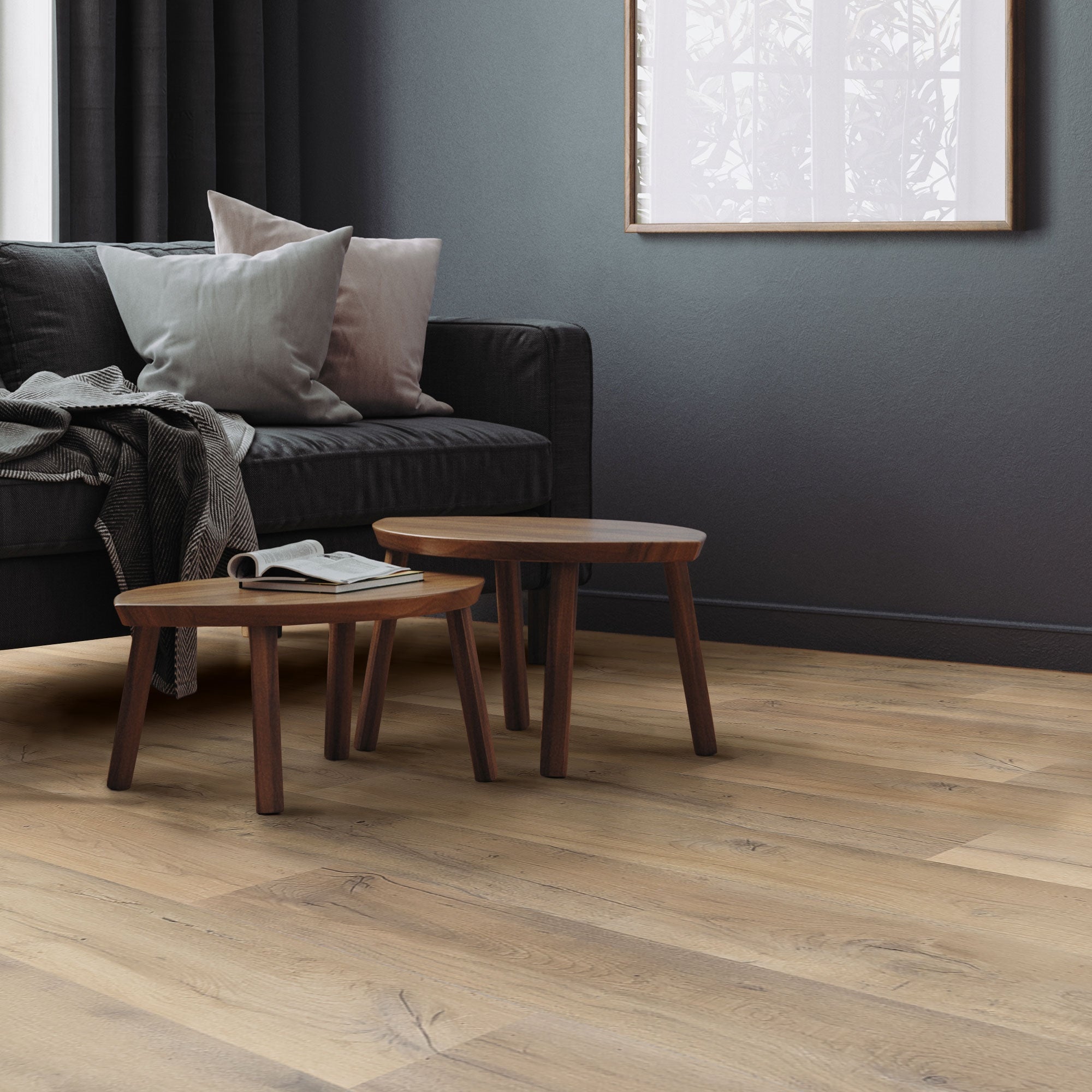 Woonkamer met bank, kussens en twee kleine tafels op een houten vloer.