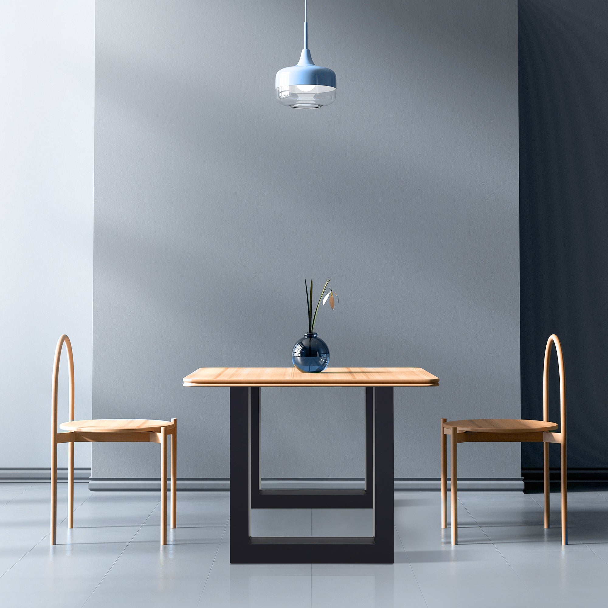 Raum mit Tisch, zwei Stühlen und einer Lampe, helle Wände und Boden.