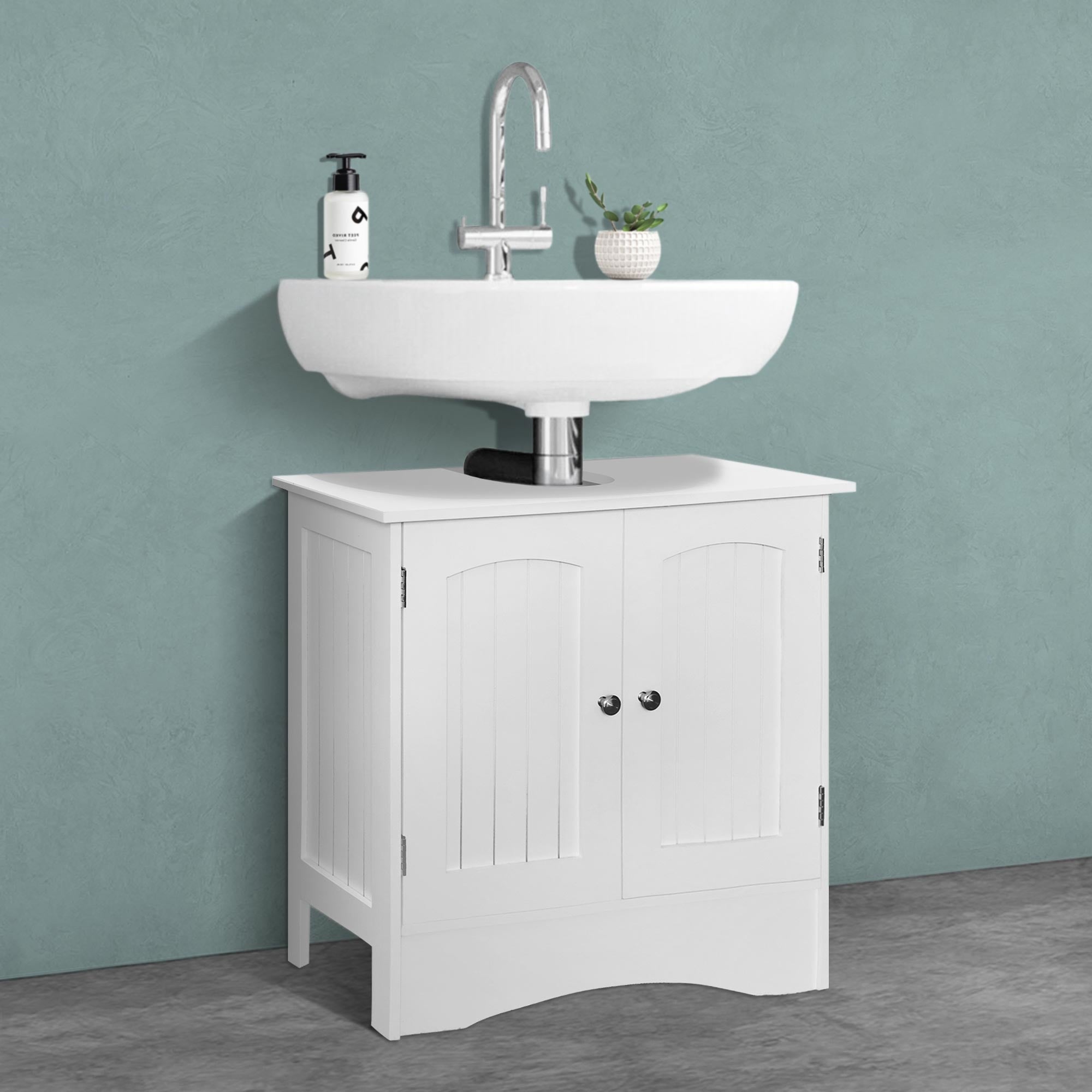 Un lavabo sur un meuble sous-vasque blanc avec une plante et du savon.