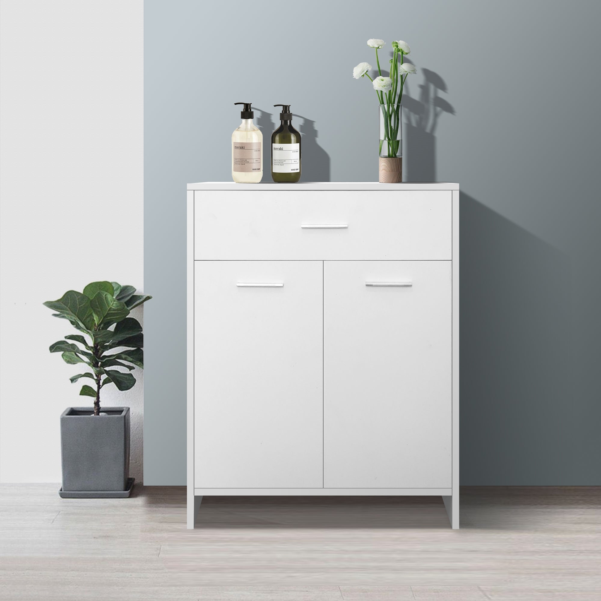 White cabinet with two doors and two drawers, decorated with plants and bottles.