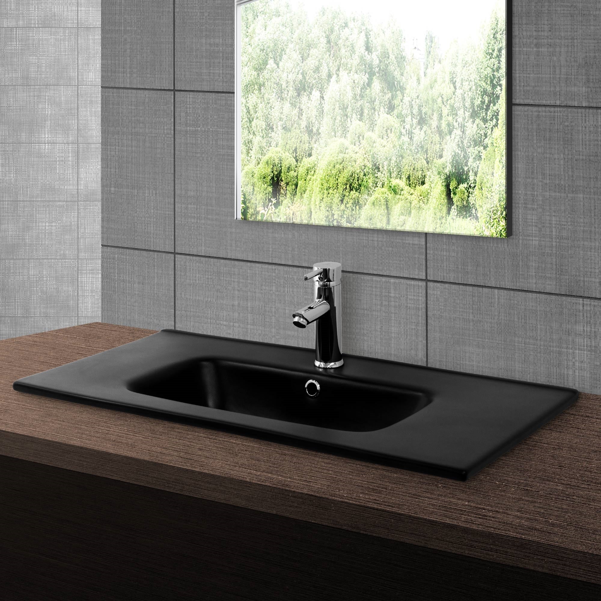Black sink with faucet in front of a window and gray tiles.