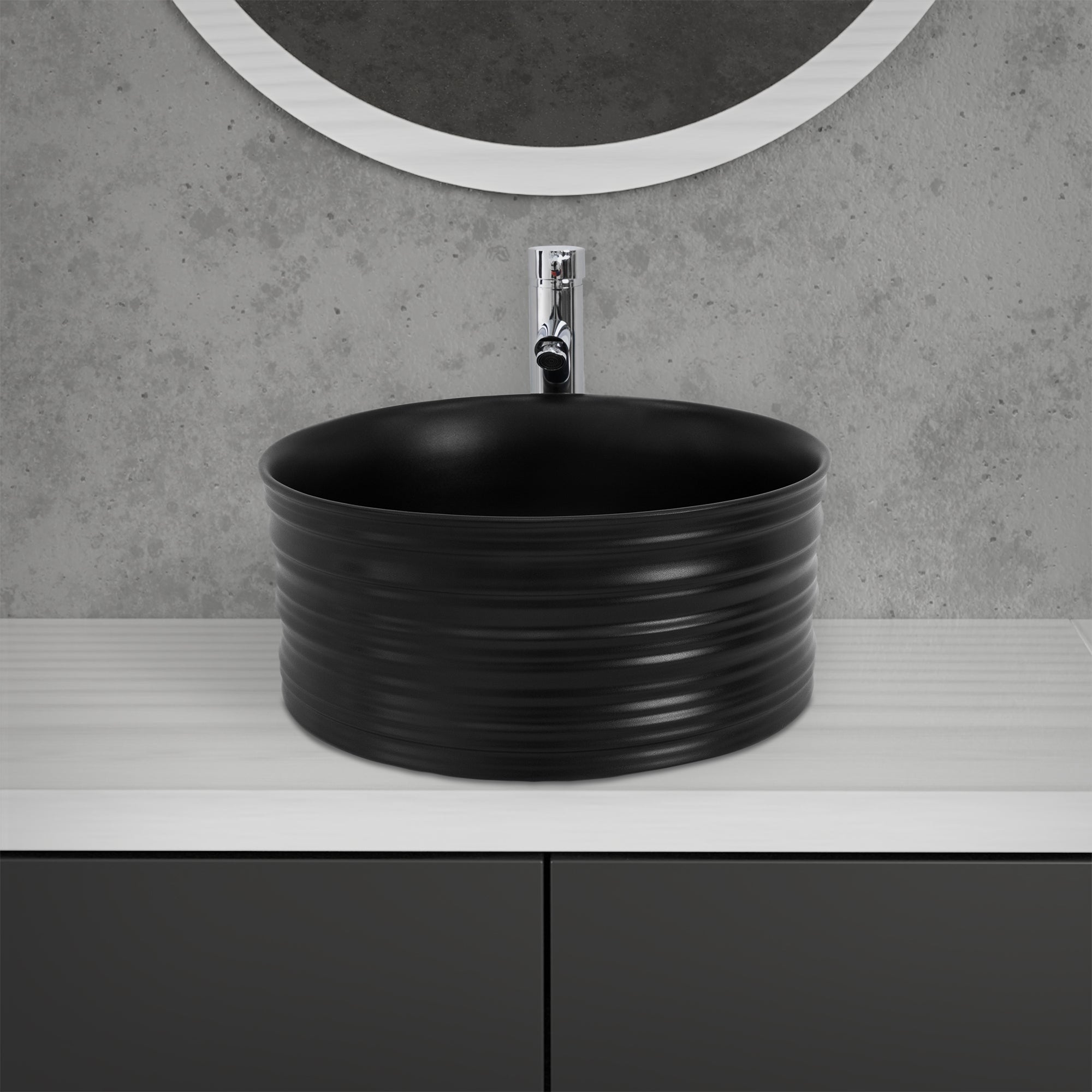 Lavabo noir et rond sur une surface blanche.