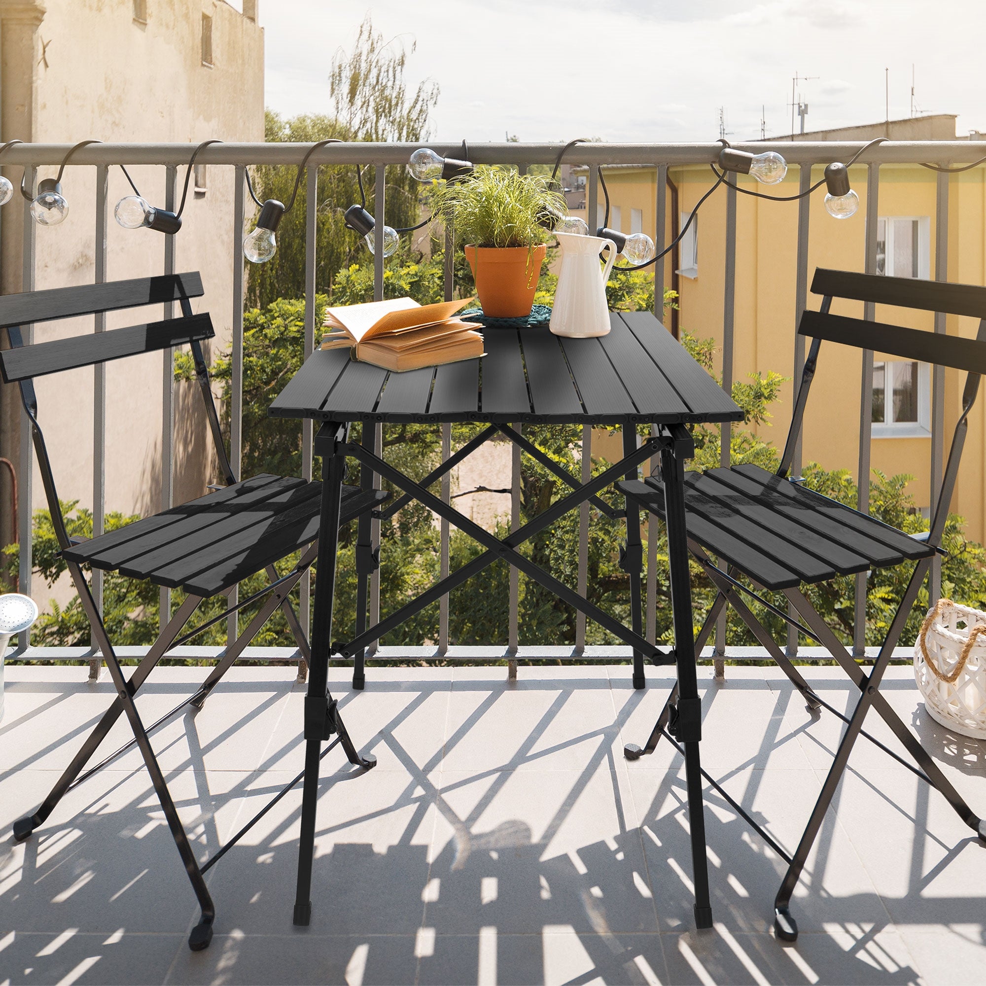 Kleiner Tisch auf einem Balkon mit Pflanzen und einem Buch.