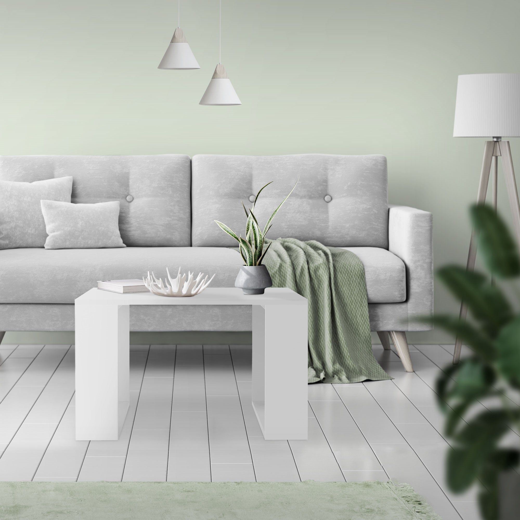 Stue med grå sofa, hvidt bord og planter på bordet.