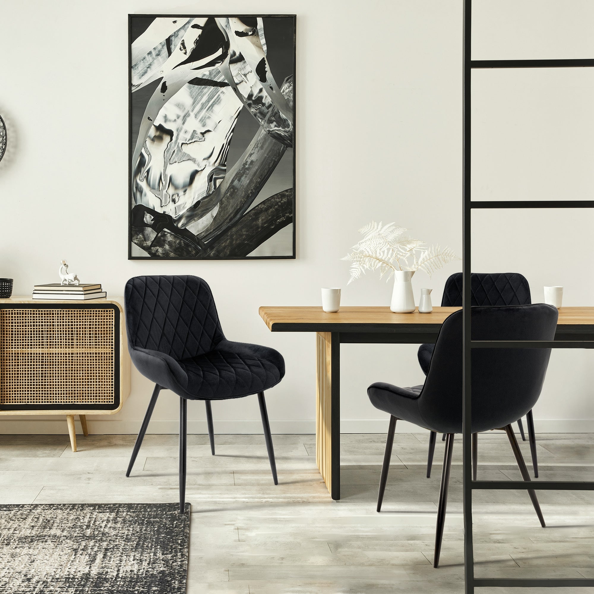 Salle à manger avec des chaises noires, une table et une œuvre murale moderne.