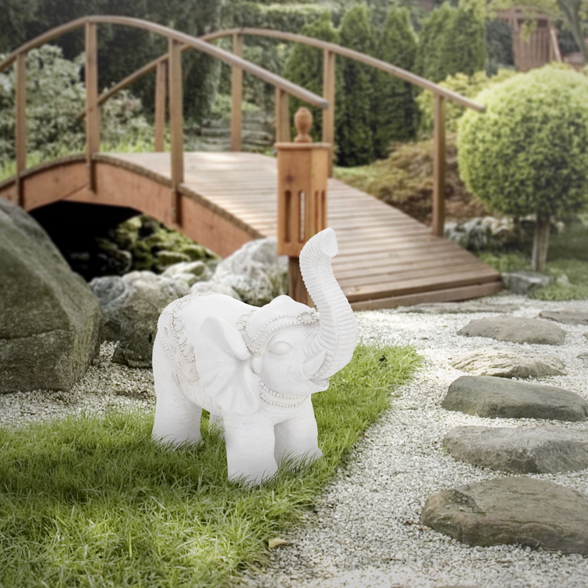 Le même éléphant sur un chemin, avec un pont en bois en arrière-plan.