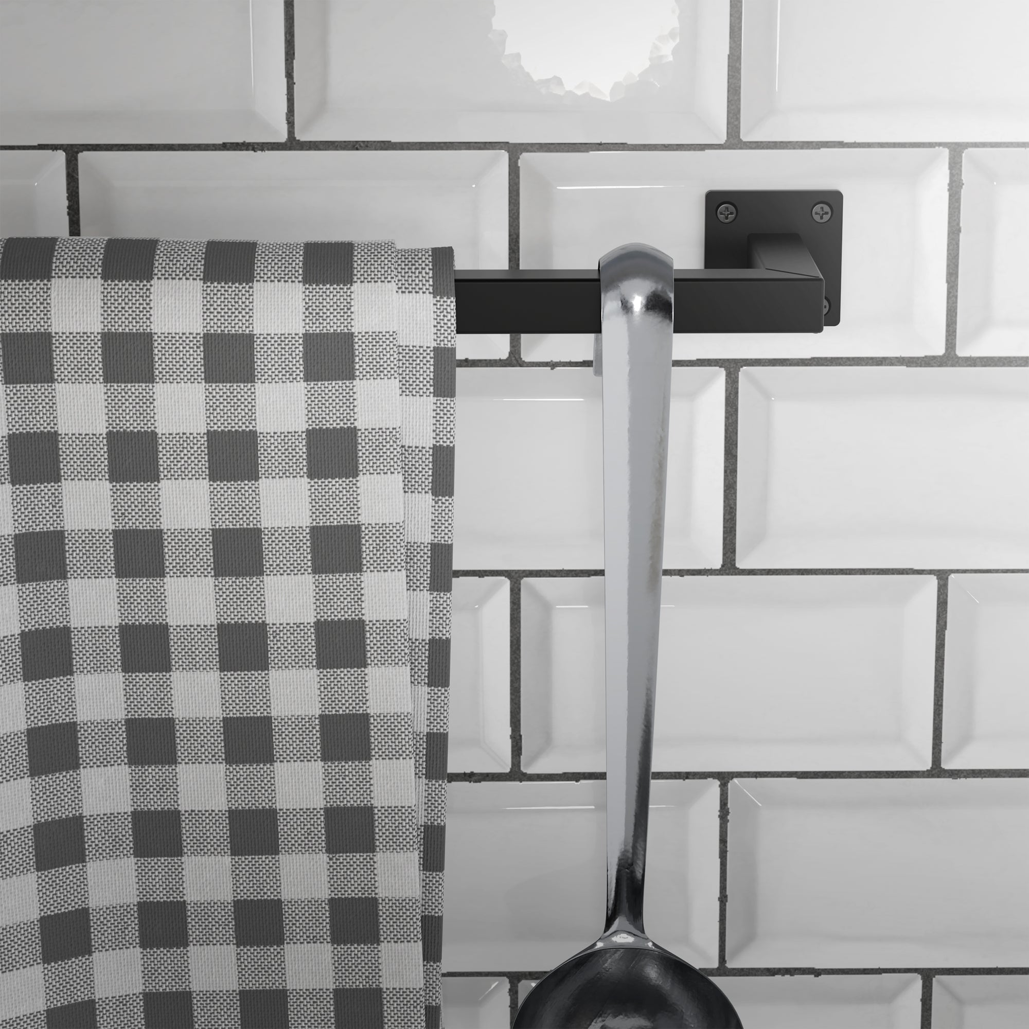Køkkenhåndklæde og ske på en sort holder på fliser.