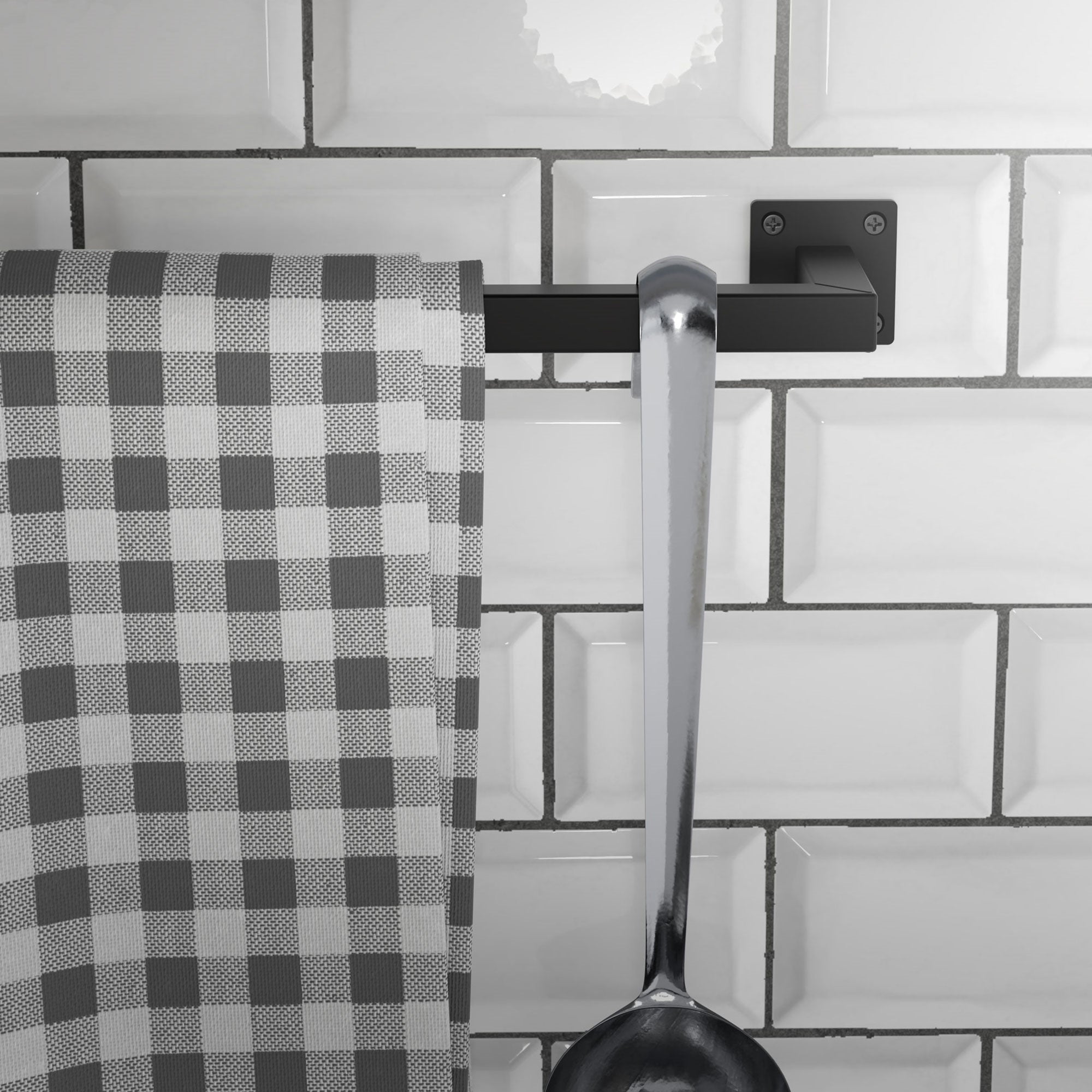 Un canovaccio da cucina pende da un supporto nero accanto a un grande cucchiaio.