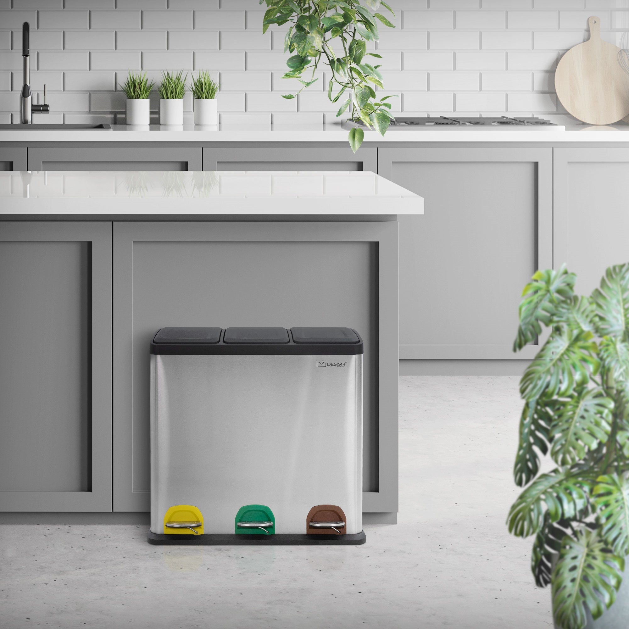 Rustfrit stål affaldsspand med tre rum og fodpedaler i et moderne køkken.