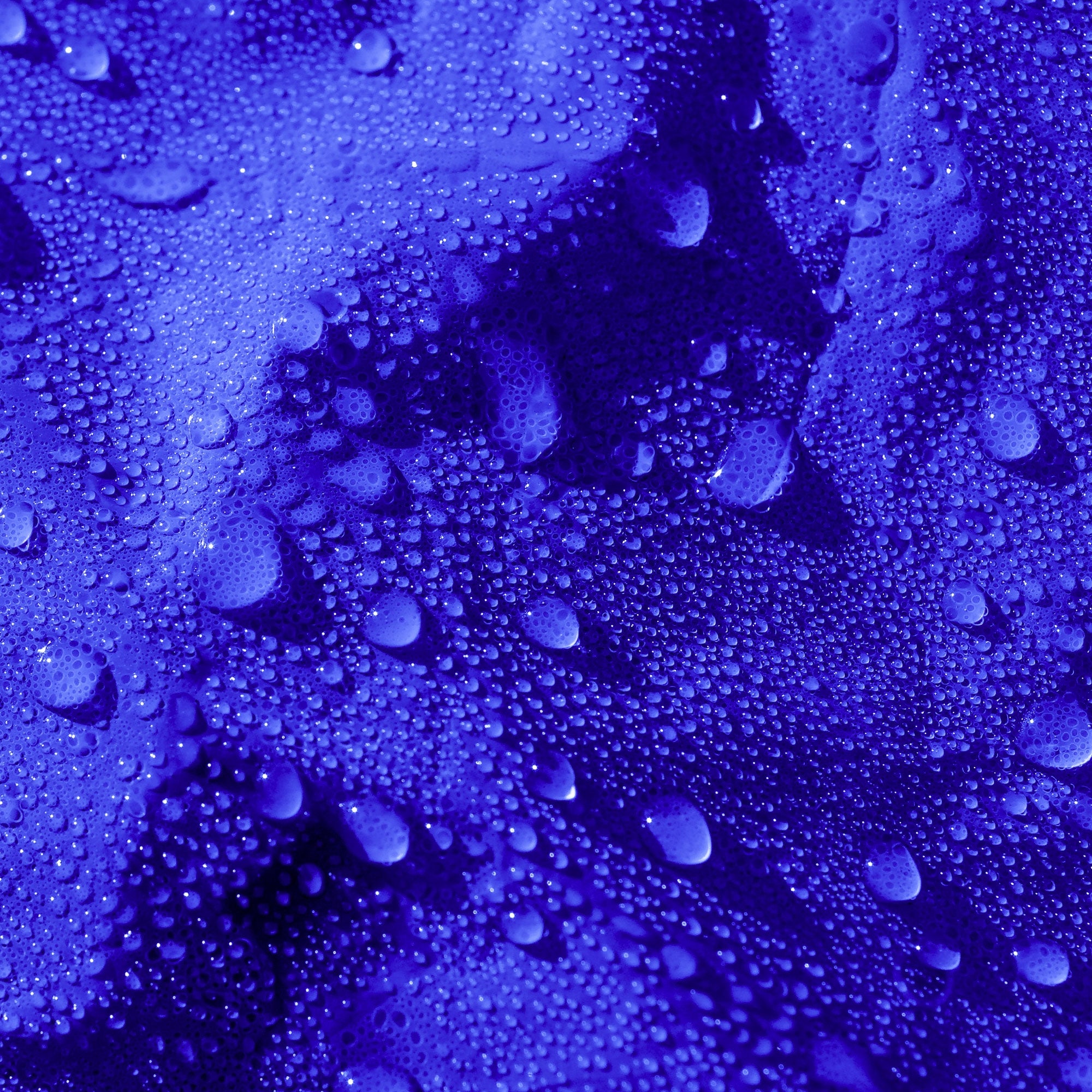 Gros plan d'une bâche bleue avec des gouttes d'eau sur la surface.