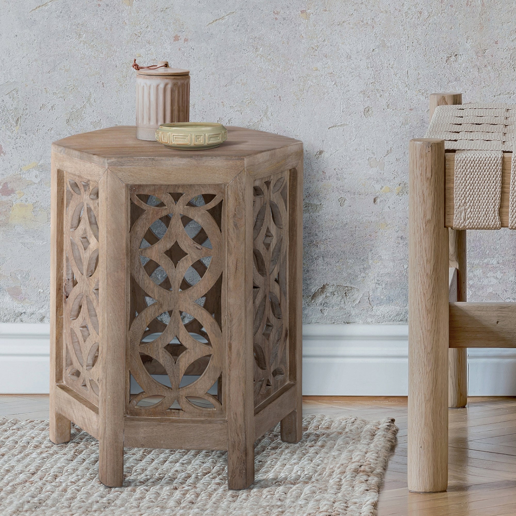 Mesa auxiliar hexagonal de madera con patrones decorativos.